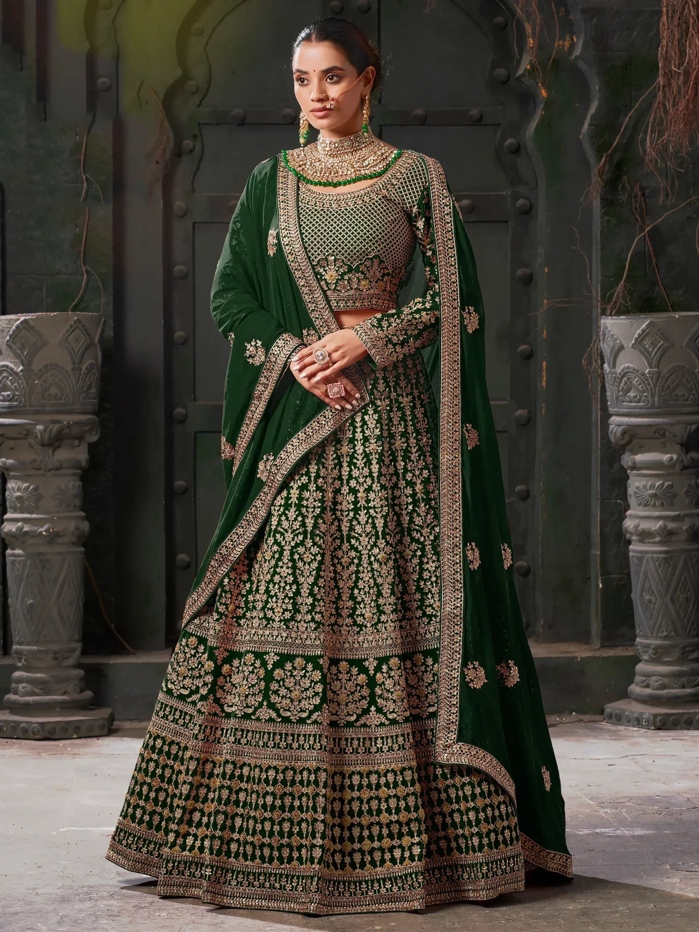 Emerald green velvet lehenga choli with gold embroidery, perfect for Indian weddings and festive occasions.