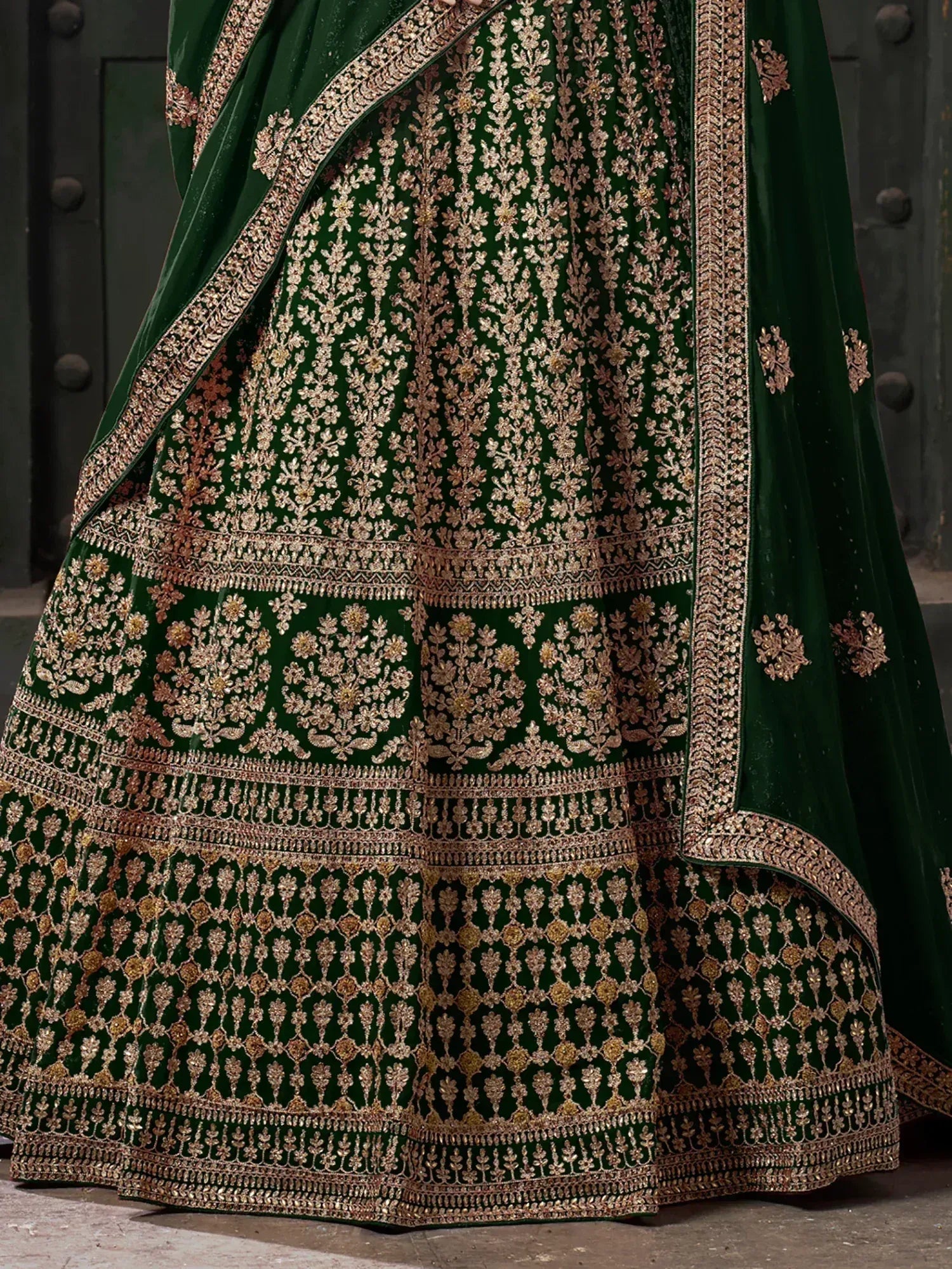 Emerald green velvet lehenga with intricate gold floral embroidery and border detailing