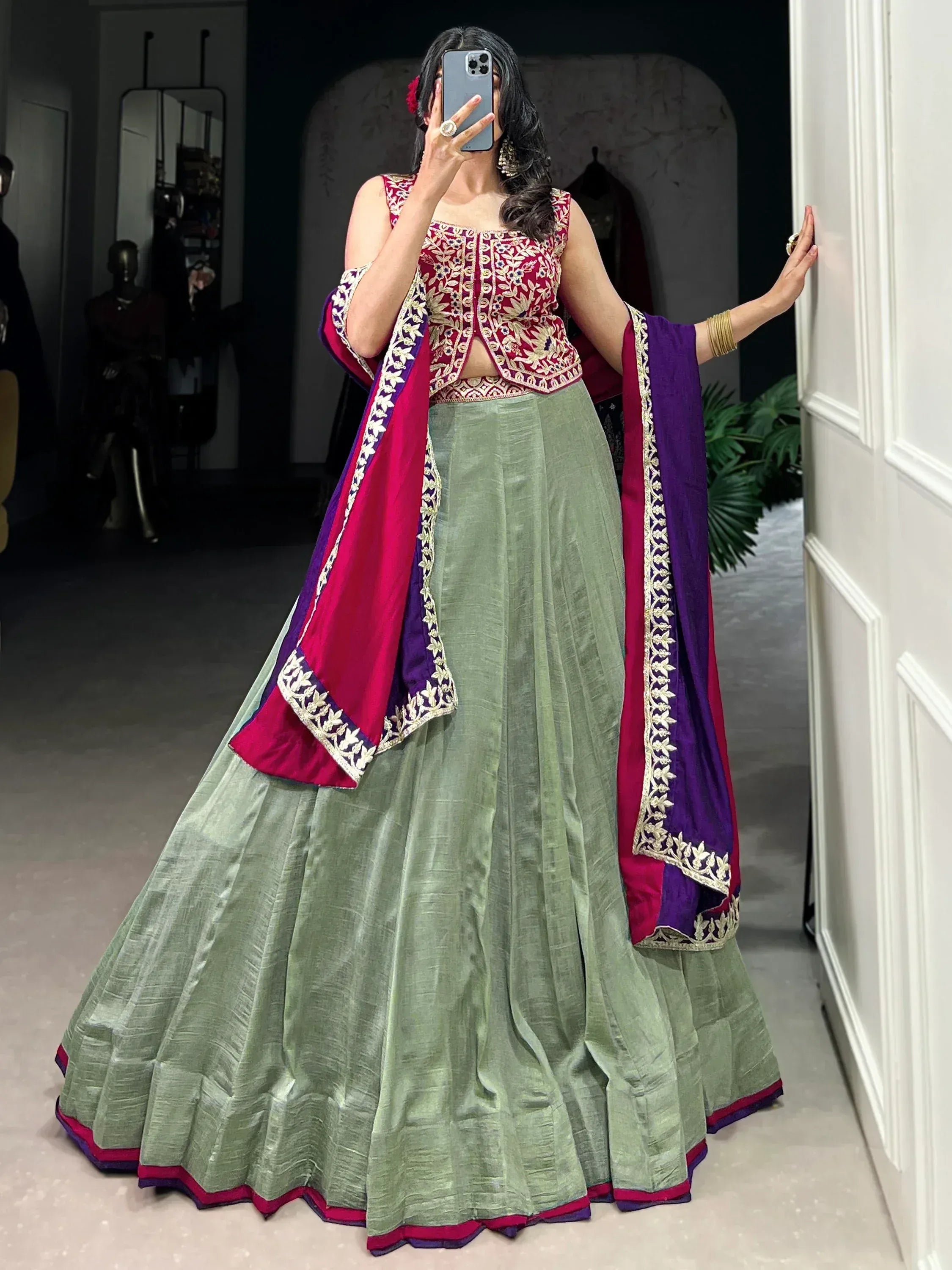 Woman in green lehenga with maroon and purple dupatta, floral embroidery, ethnic Indian wear
