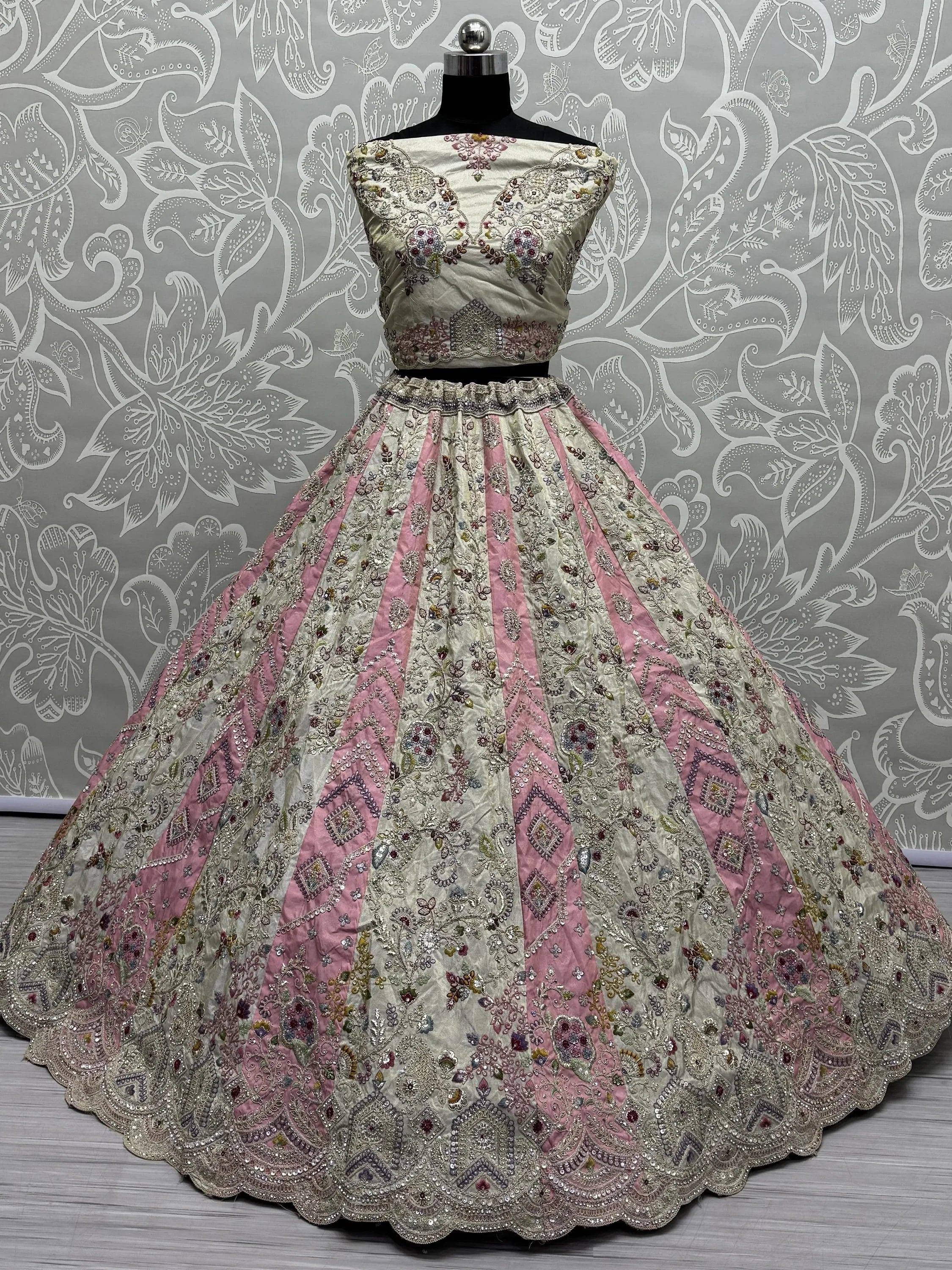 Elegant ivory and pink embroidered lehenga choli with floral motifs and scalloped hem, displayed on mannequin.