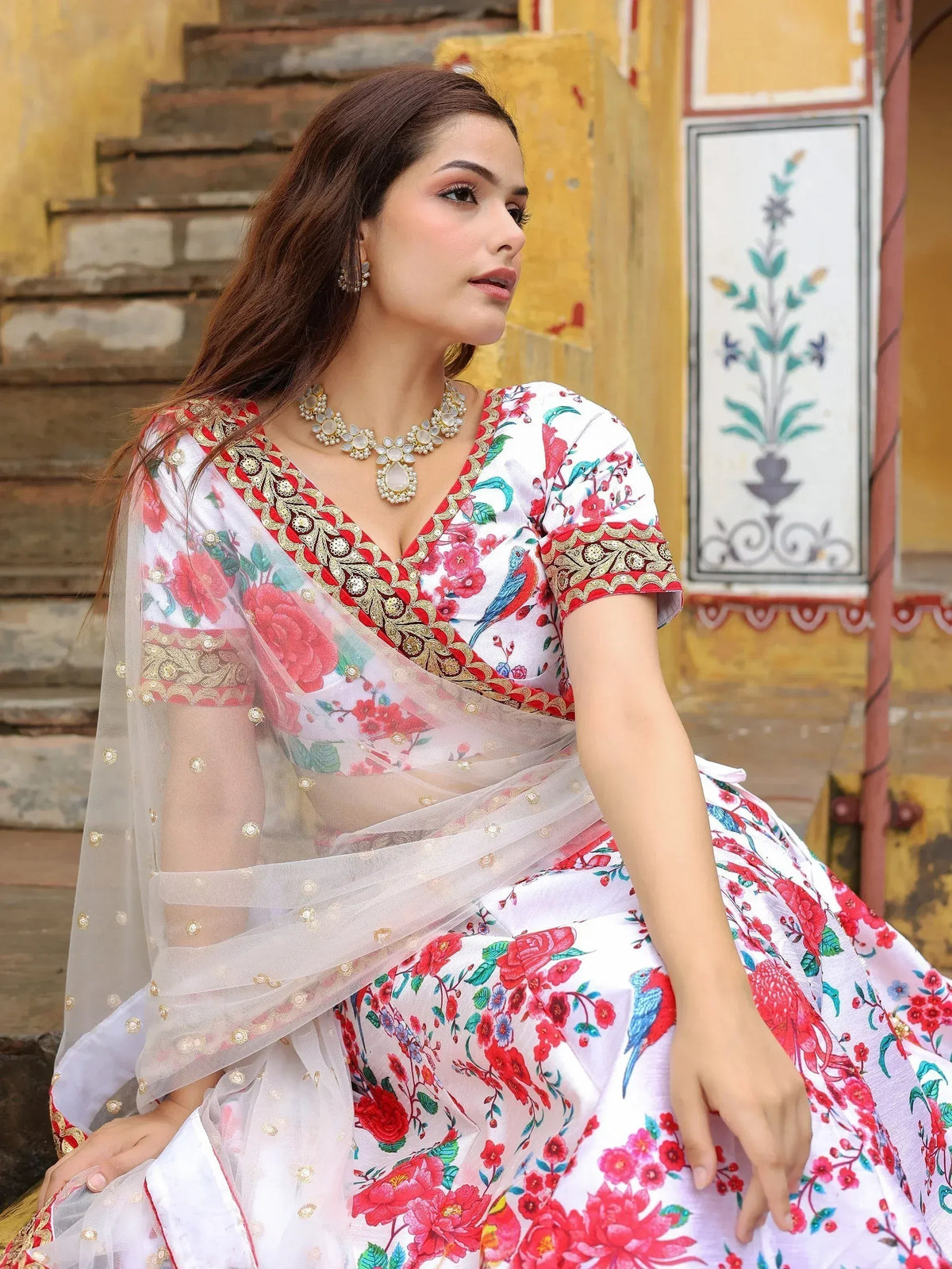 Woman in white floral lehenga choli with red gold embroidery, sheer dupatta, traditional Indian ethnic wear