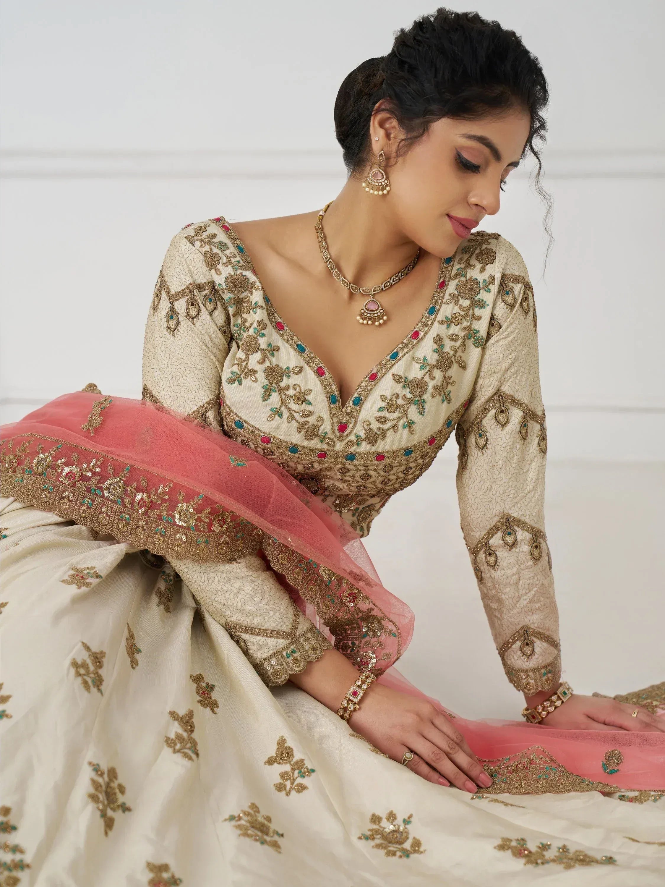 Elegant cream lehenga choli with gold embroidery and pink dupatta, perfect for Indian ethnic wear occasions.