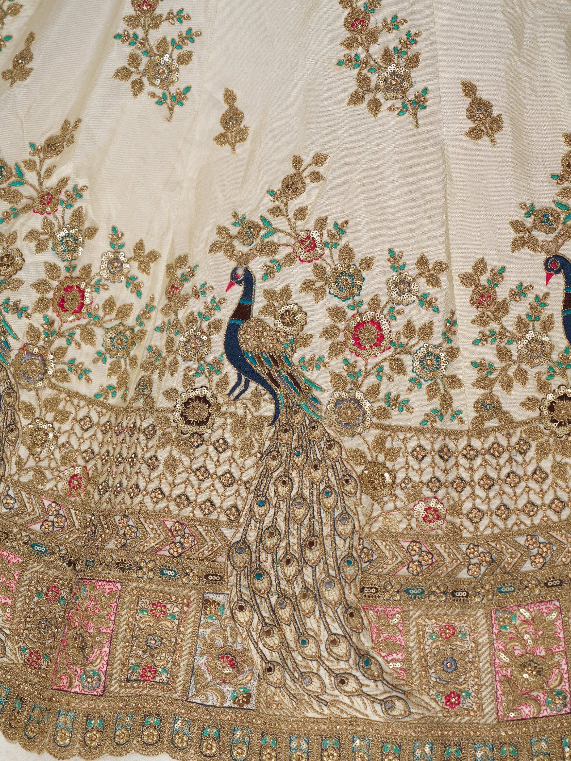 Cream lehenga with peacock embroidery, floral motifs, and gold sequin work for Indian ethnic wear