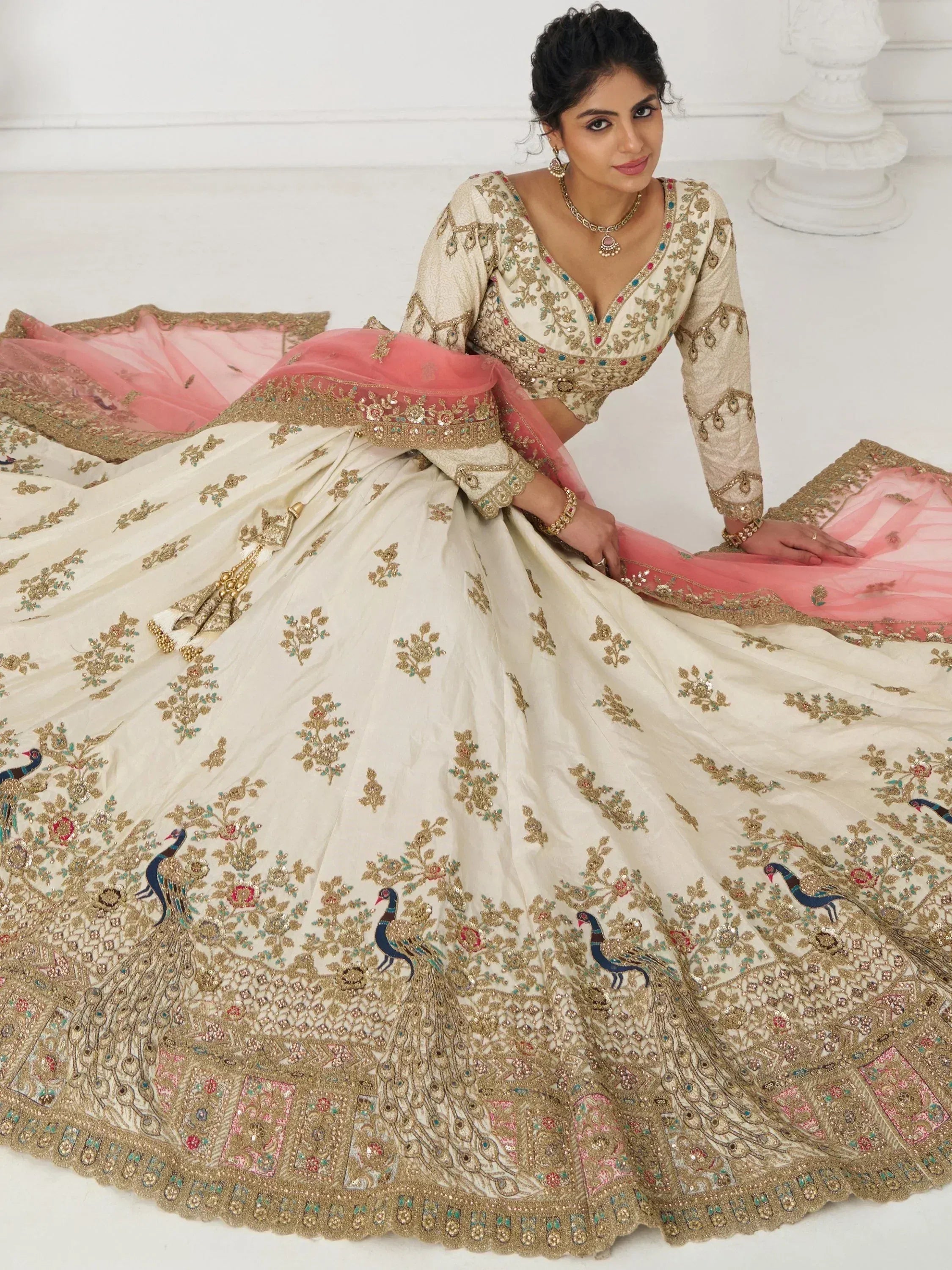 Cream designer lehenga choli with peacock embroidery, gold embellishments, and pink dupatta for Indian ethnic wear.