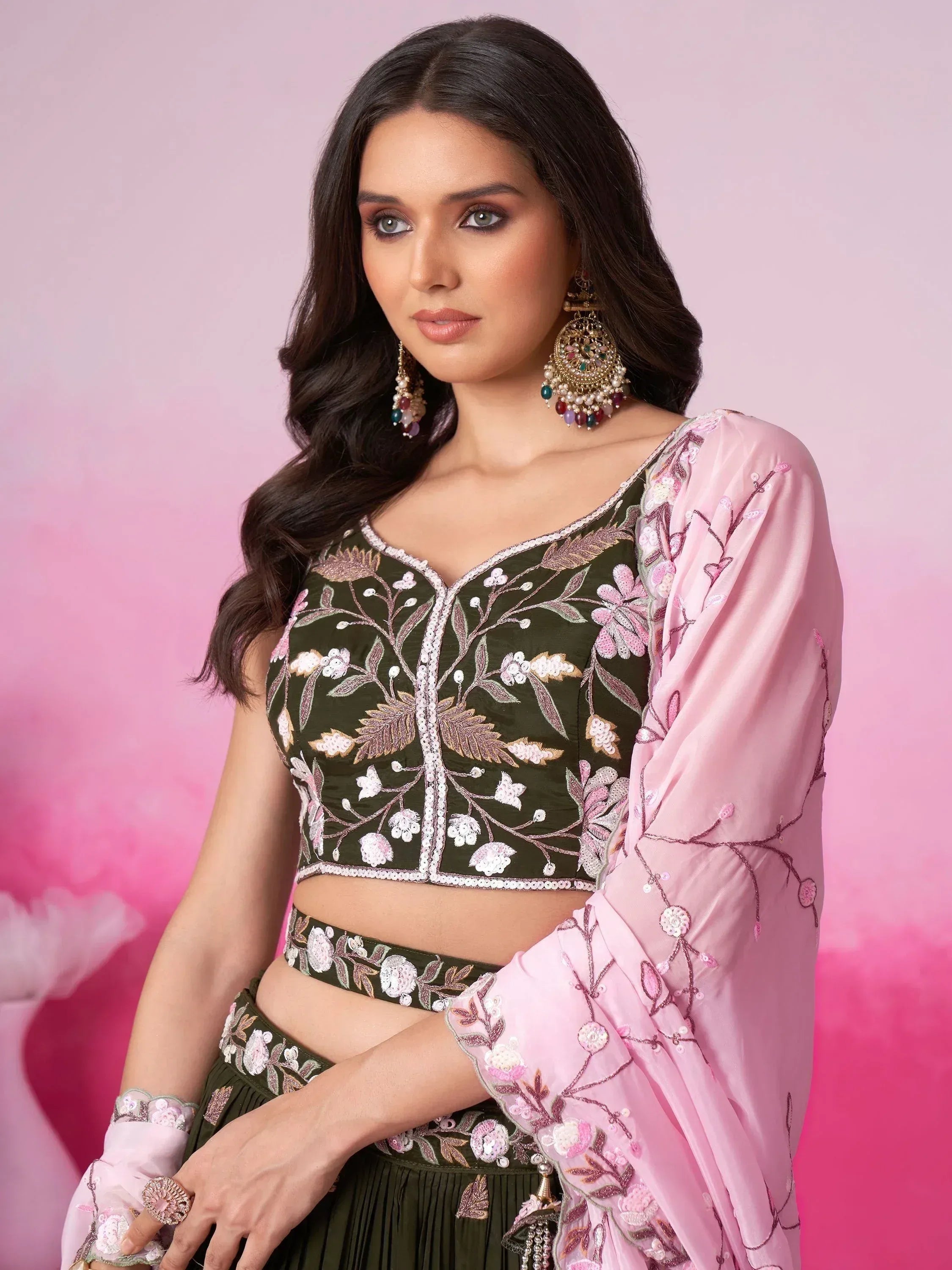 Olive green embroidered lehenga choli with pink dupatta, floral embellishments, and statement earrings