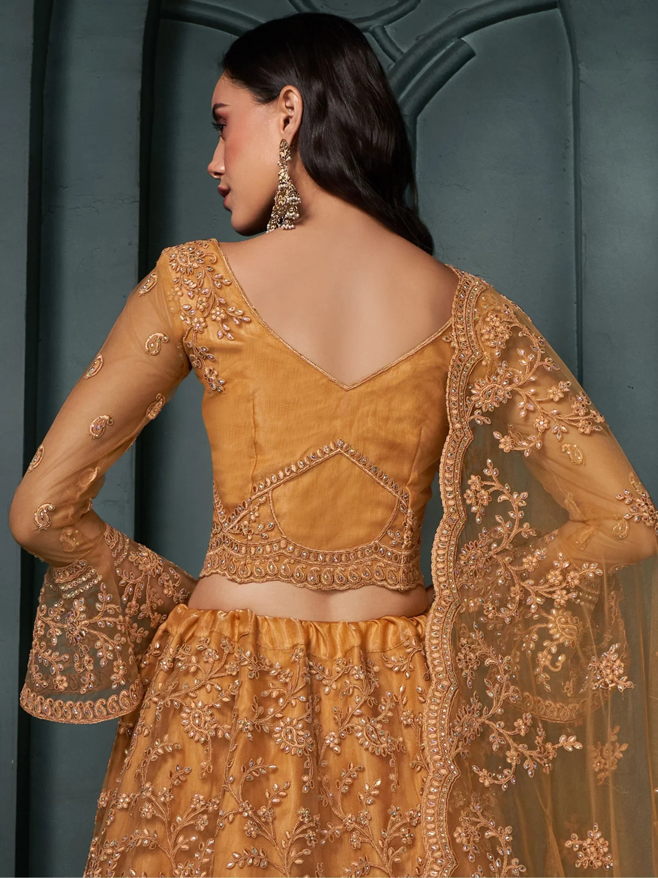 Golden embroidered lehenga choli with sheer sleeves and back detailing, perfect for Indian ethnic wear.