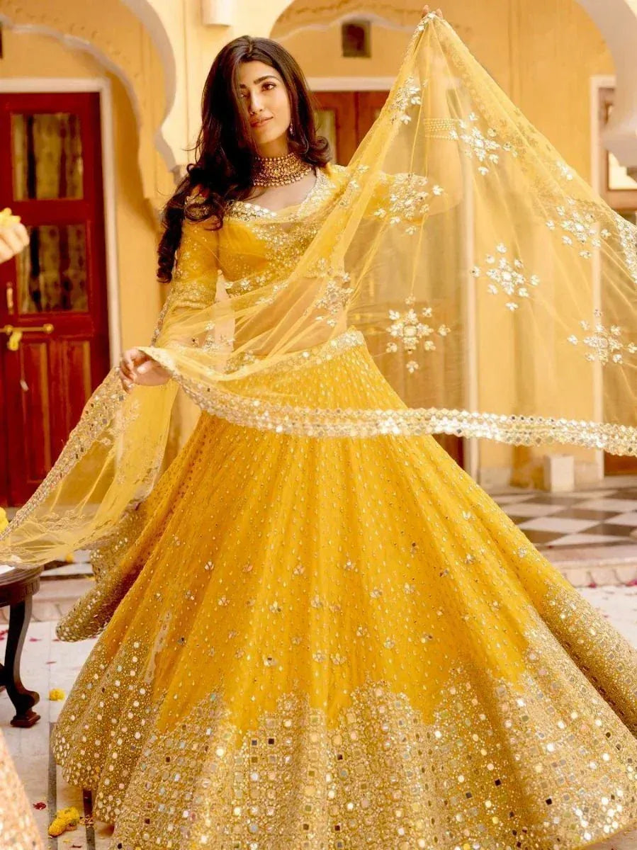 Yellow designer lehenga choli with mirror work and sheer dupatta, perfect for Indian weddings and festive occasions