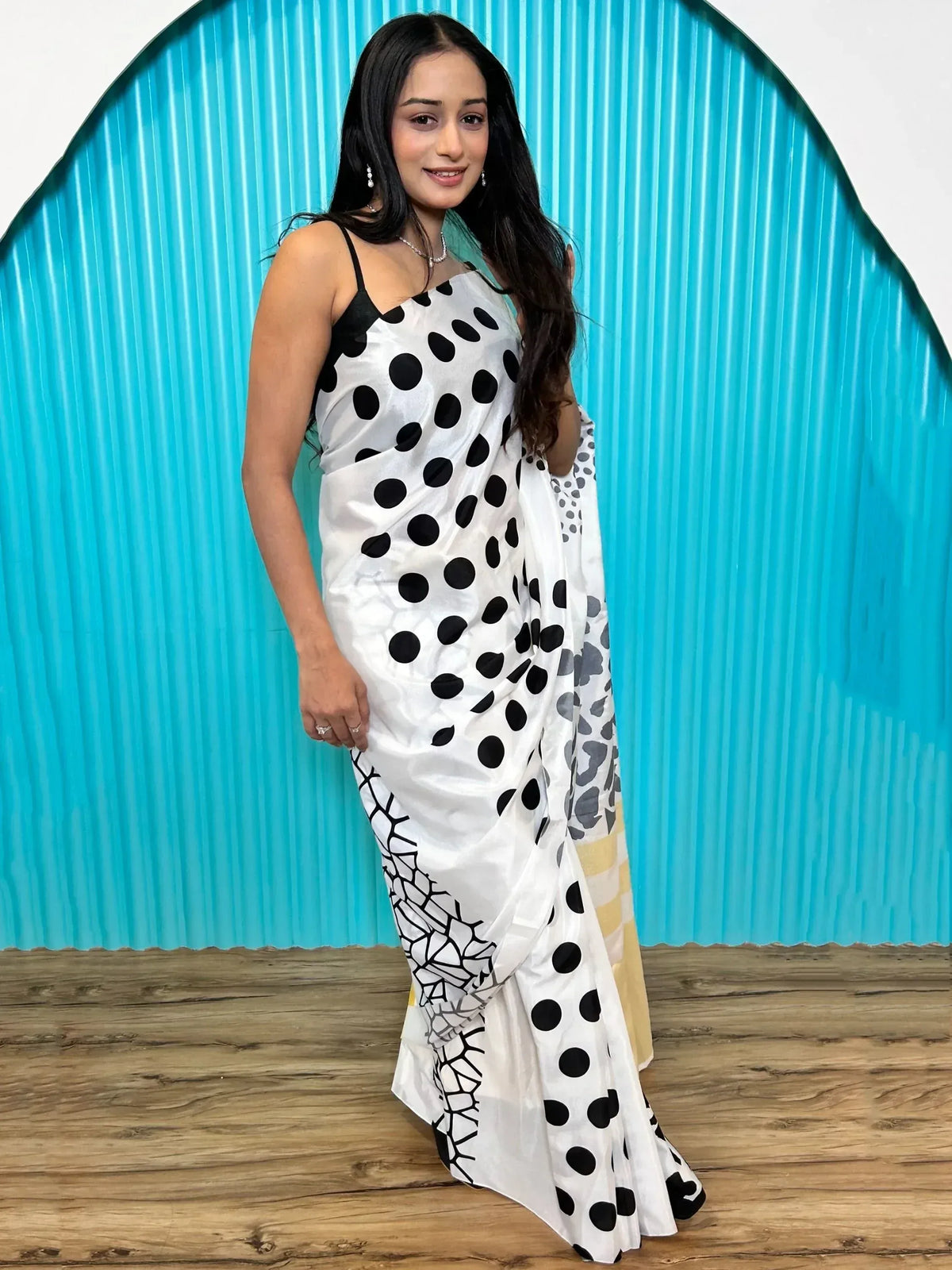 White saree with black polka dots and geometric border, styled with black spaghetti top