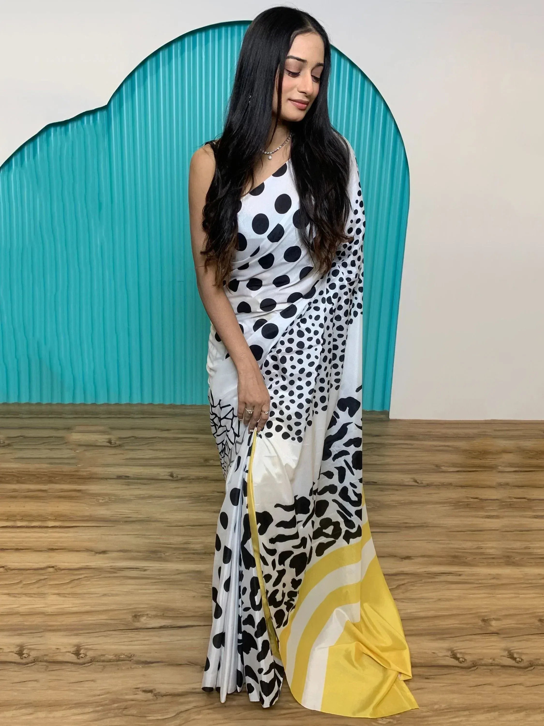 White saree with black polka dots and yellow border, styled with a sleeveless blouse