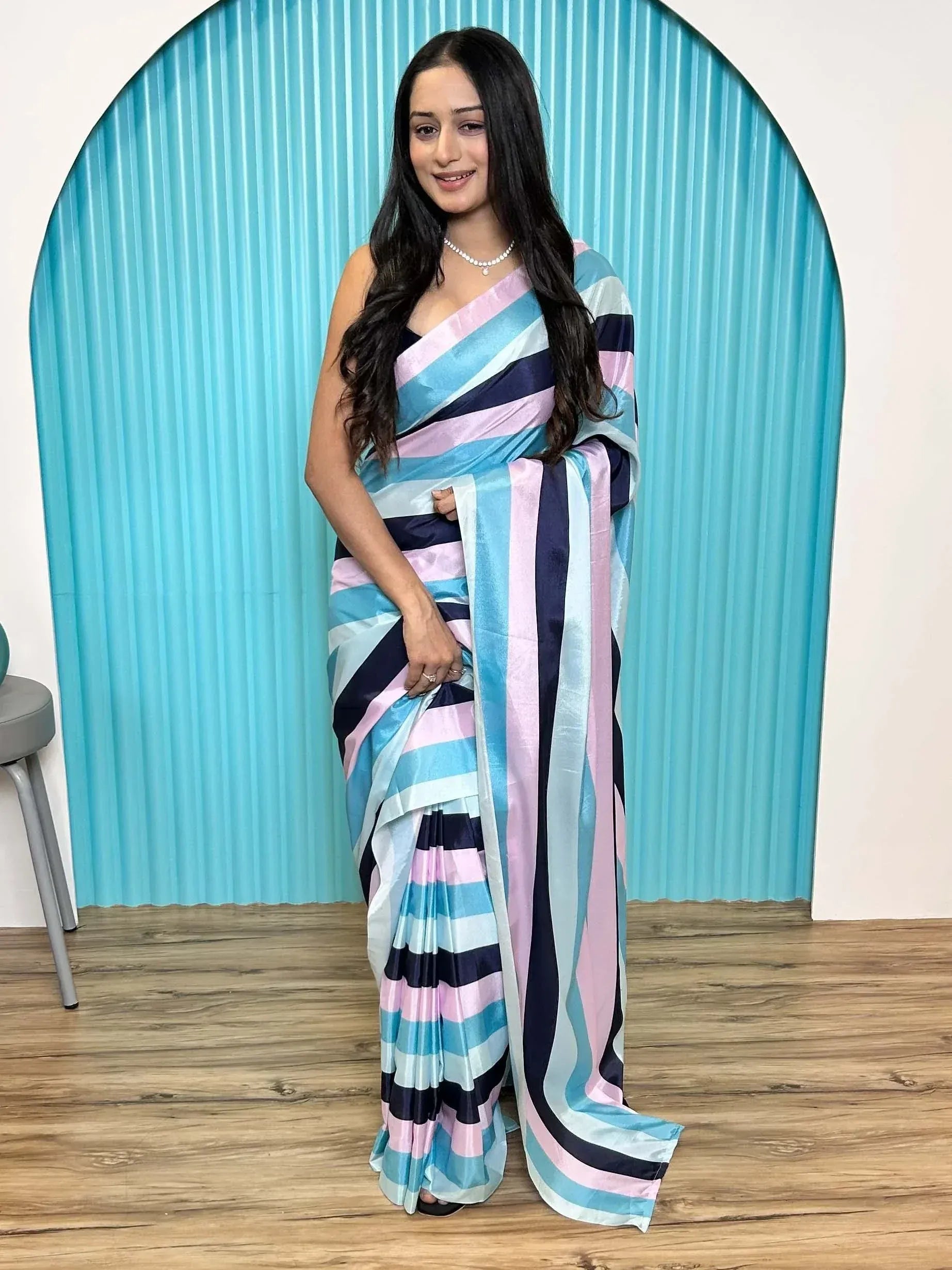 Woman in striped saree with pink, blue, and navy hues, styled for ethnic wear