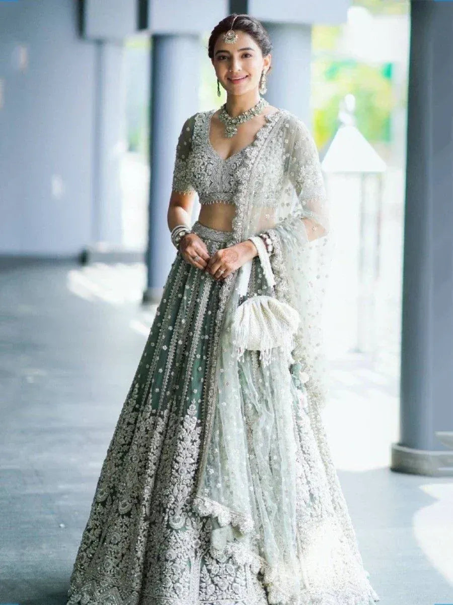 Elegant silver and green embroidered lehenga choli with sheer dupatta, perfect for Indian weddings and festive occasions.