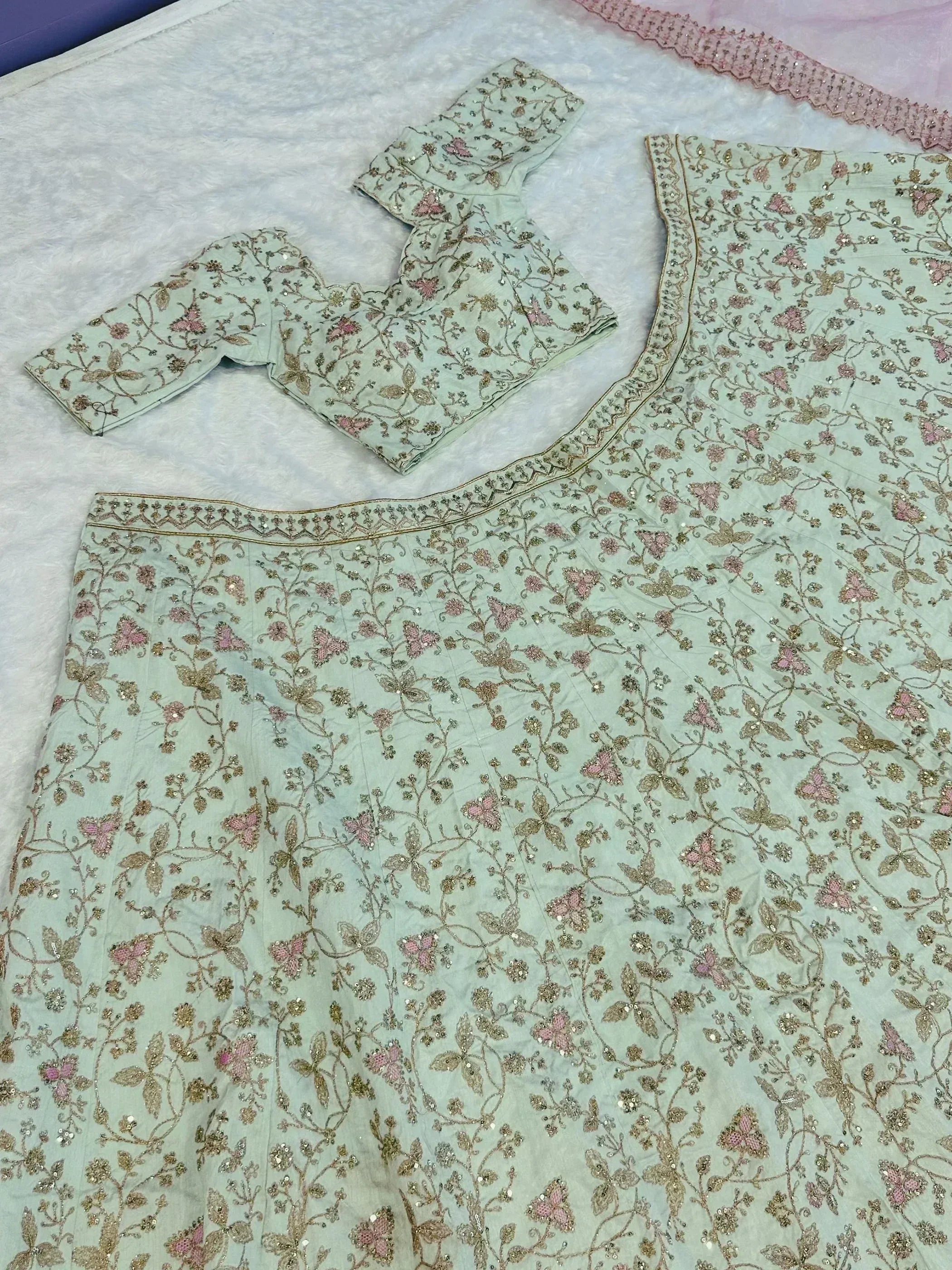 Mint green embroidered lehenga choli with pink floral motifs and gold detailing, perfect for Indian ethnic wear.