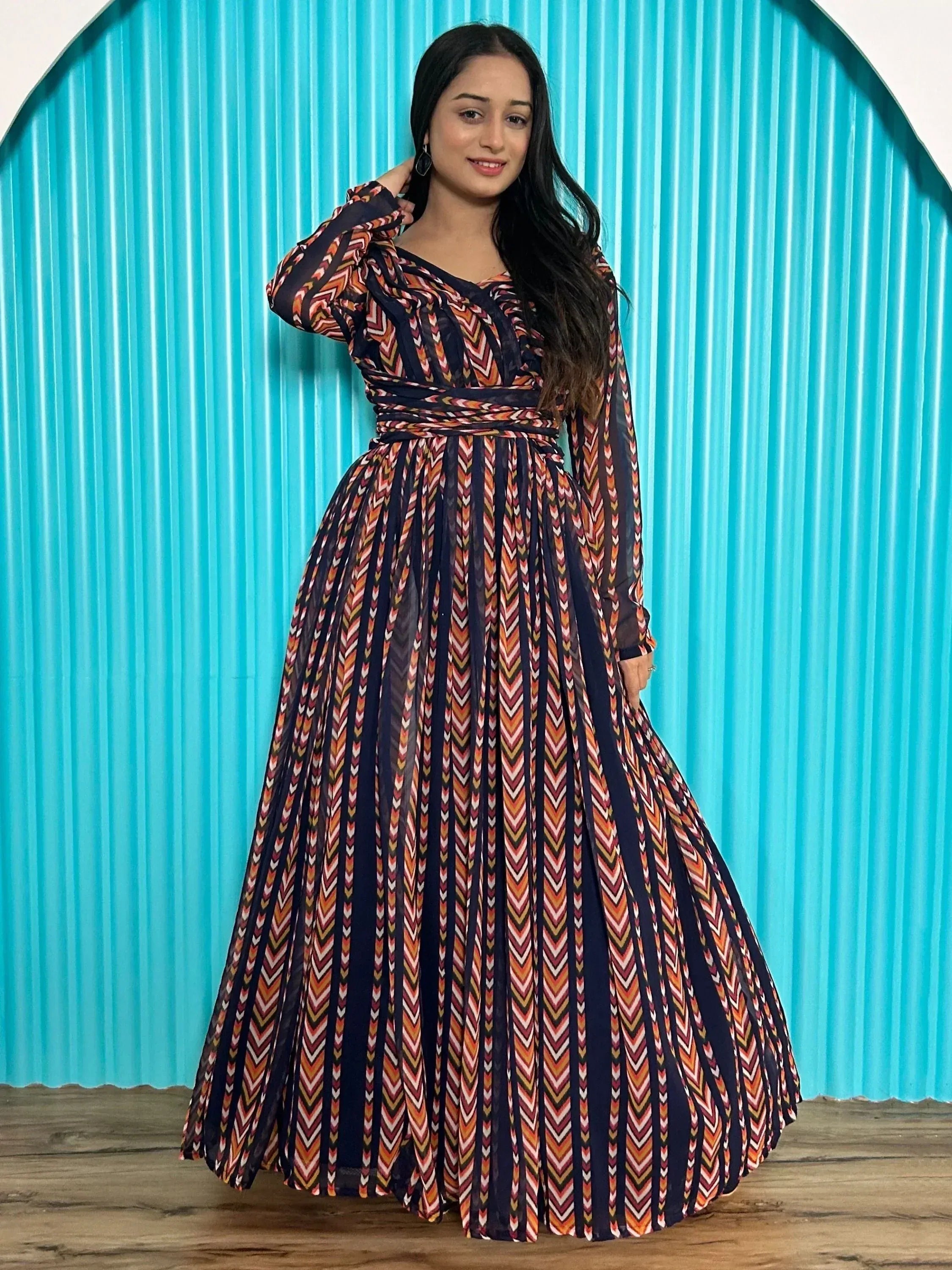 Woman in long ethnic gown with geometric print, pleated skirt, and wrap waist, ideal for Indian occasions.