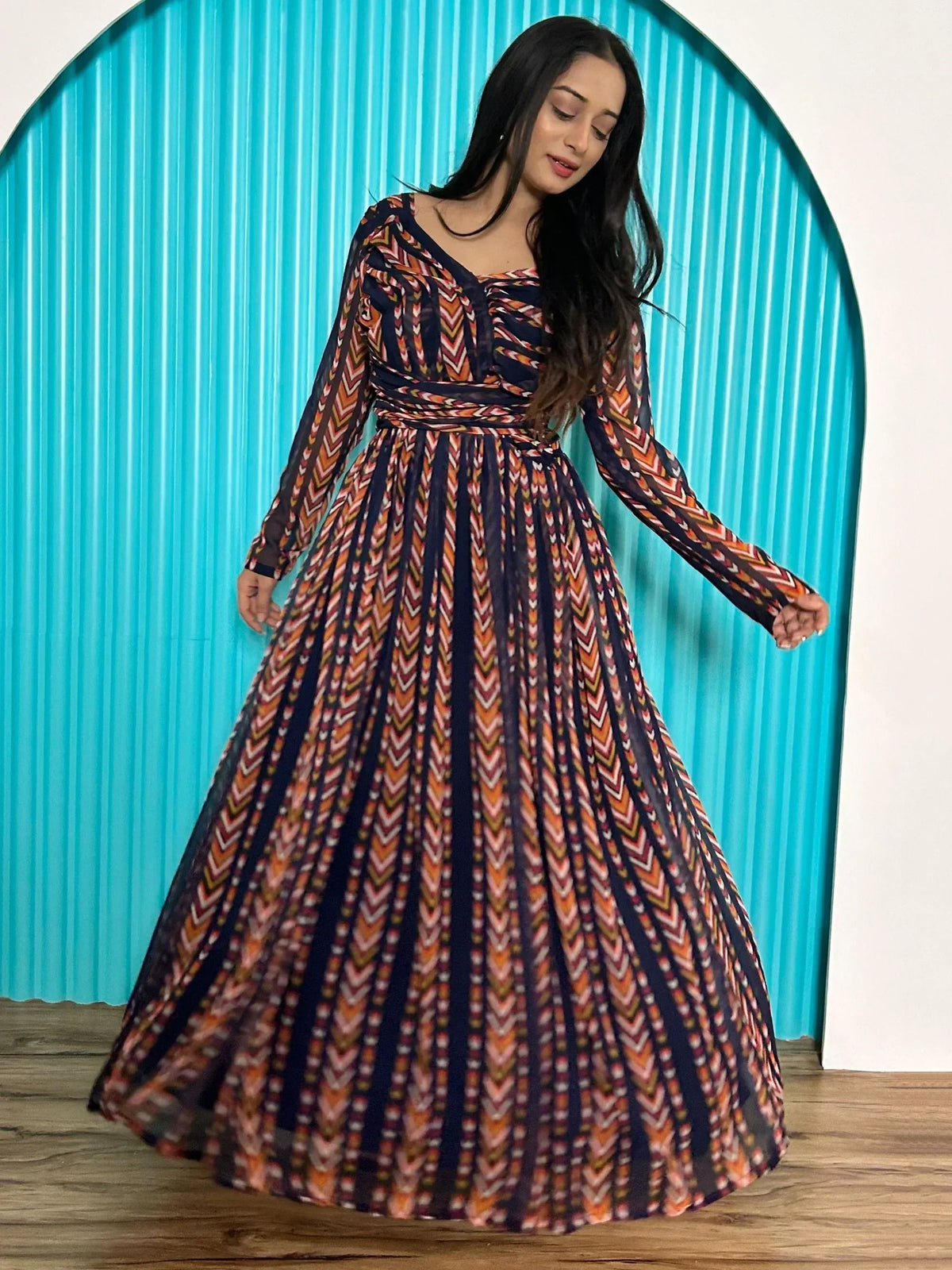 Woman in ethnic printed gown with long sleeves and pleated skirt, perfect for Indian occasions