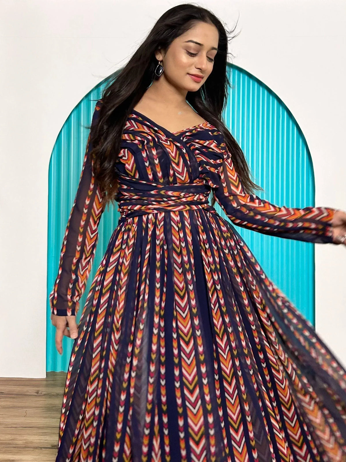 Woman in colorful ethnic print gown with long sleeves and pleated skirt, perfect for festive occasions.