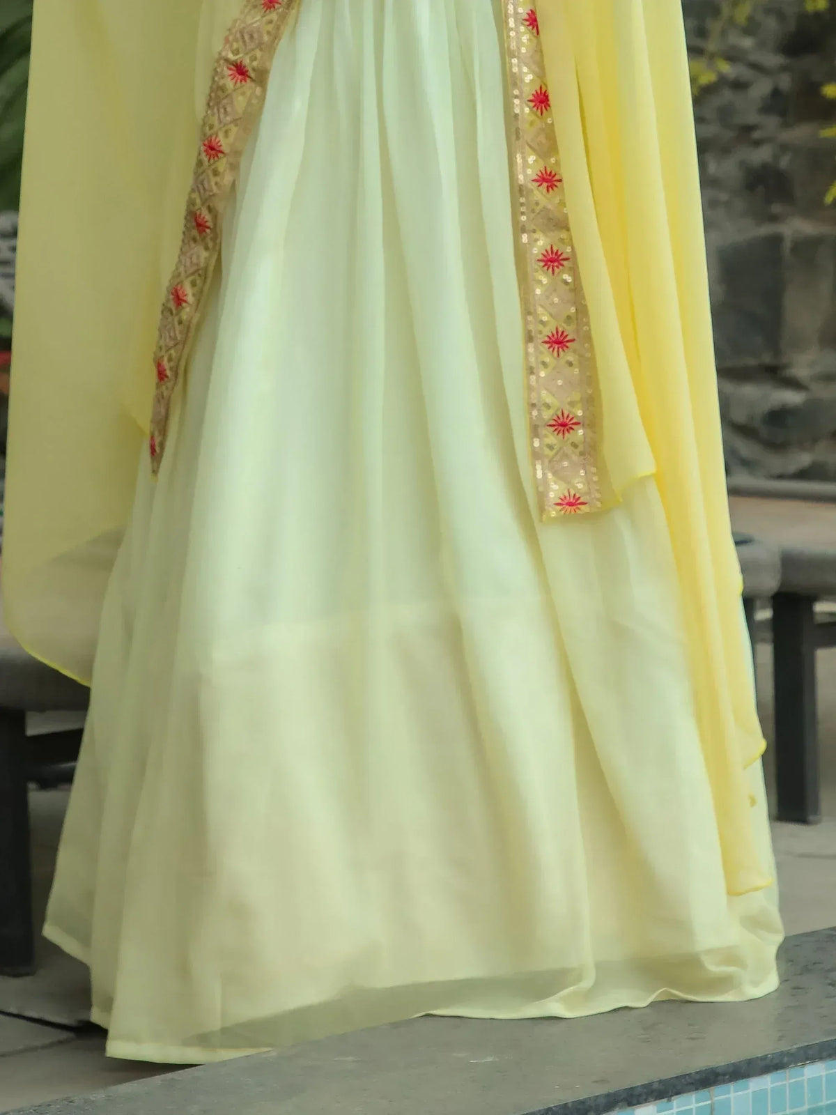 Yellow ethnic gown with red floral embroidery and gold sequin border, perfect for Indian celebrations