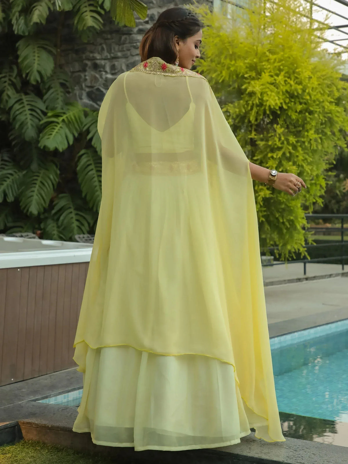Yellow ethnic gown with cape, perfect for Indian occasions, featuring delicate embroidery and layered skirt.
