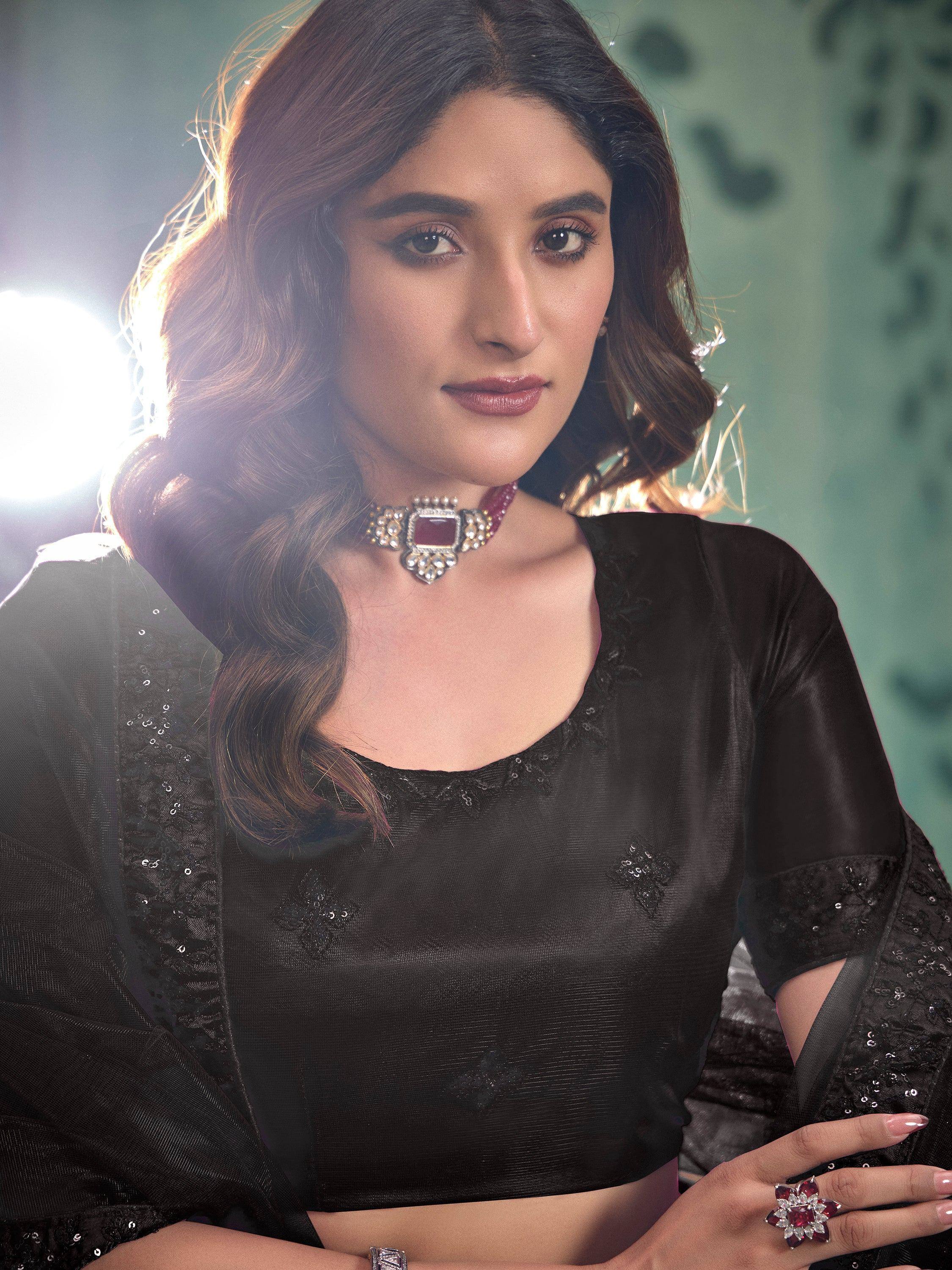 Elegant woman in black ethnic blouse with sequin detailing, styled with statement jewelry for festive occasions.