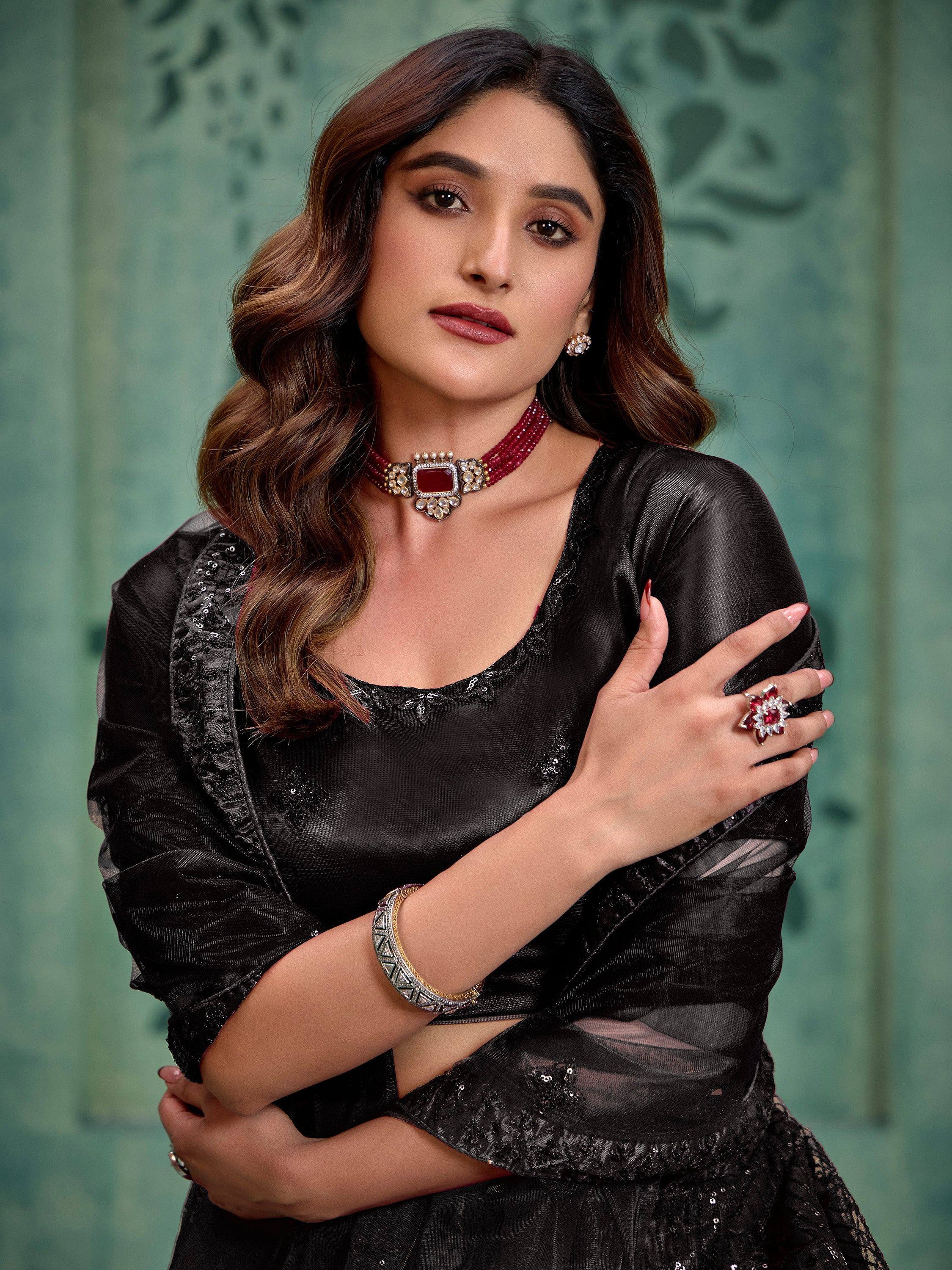 Elegant woman in black ethnic gown with red gemstone jewelry, perfect for Indian festive occasions.