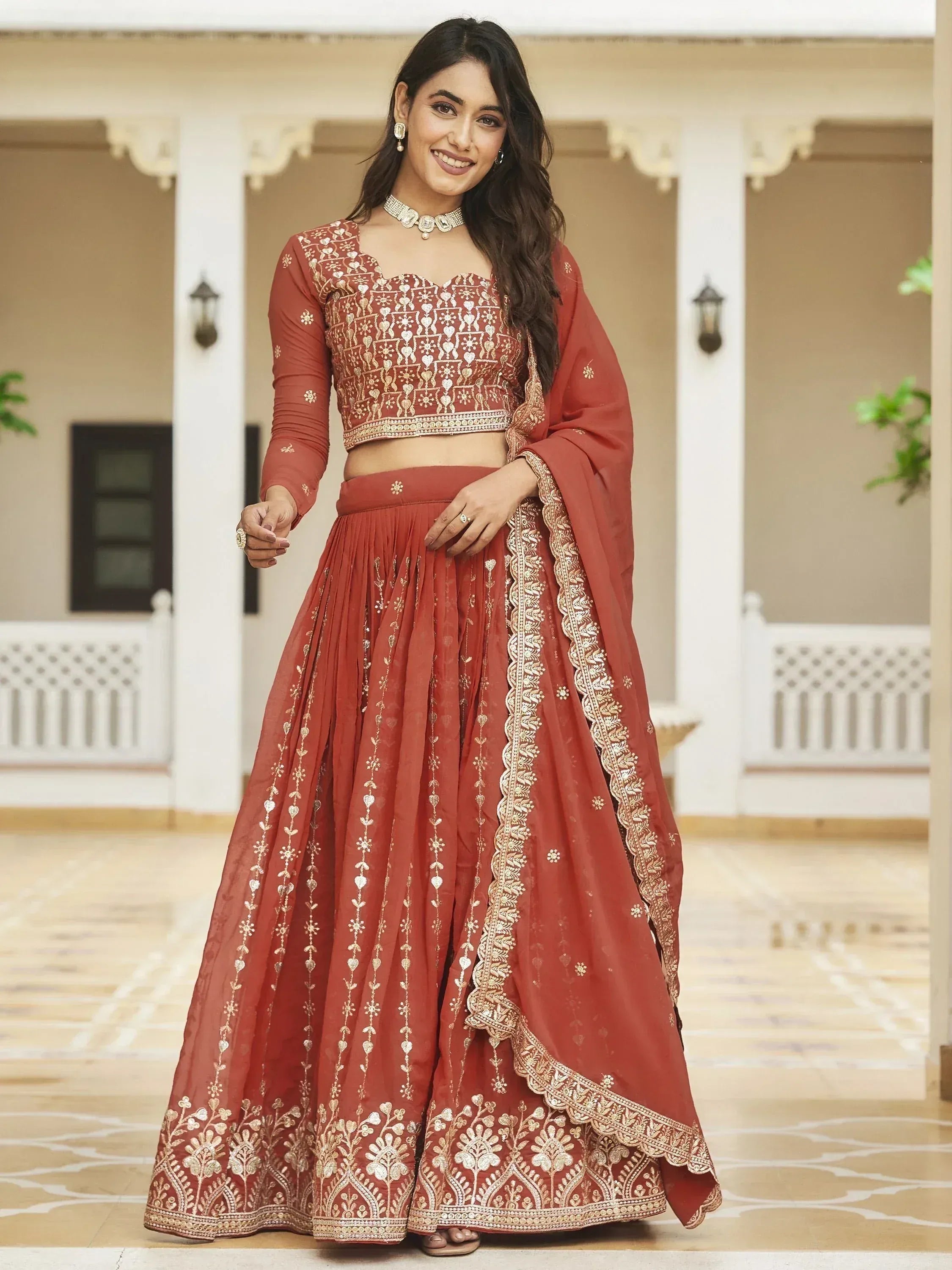 Elegant terracotta lehenga choli with gold embroidery, perfect for Indian weddings and festive occasions.