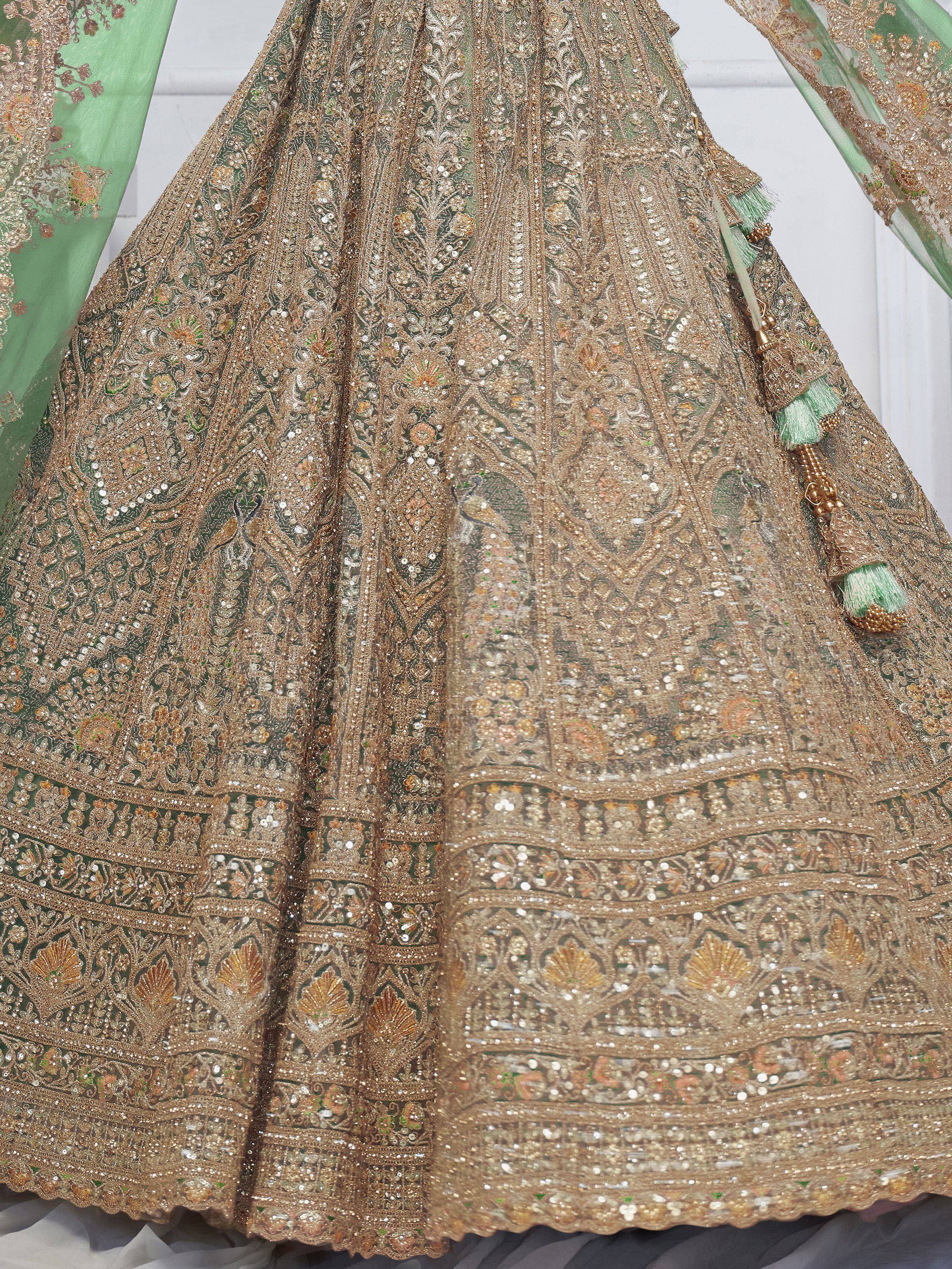 Designer lehenga choli with intricate gold embroidery, sequins, and peacock motifs on green fabric