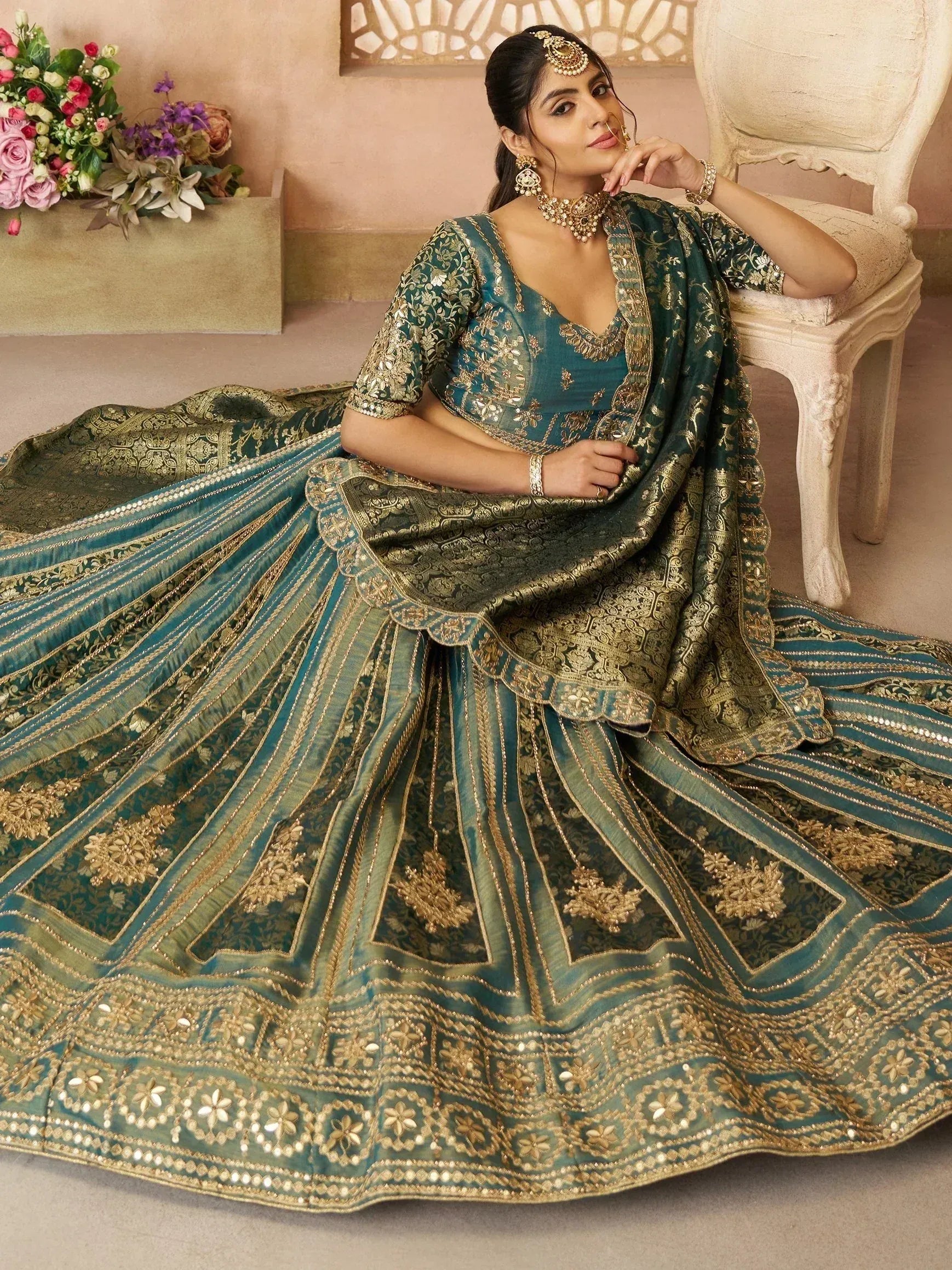 Teal and gold embroidered lehenga choli with intricate floral patterns, perfect for Indian weddings and festive occasions.