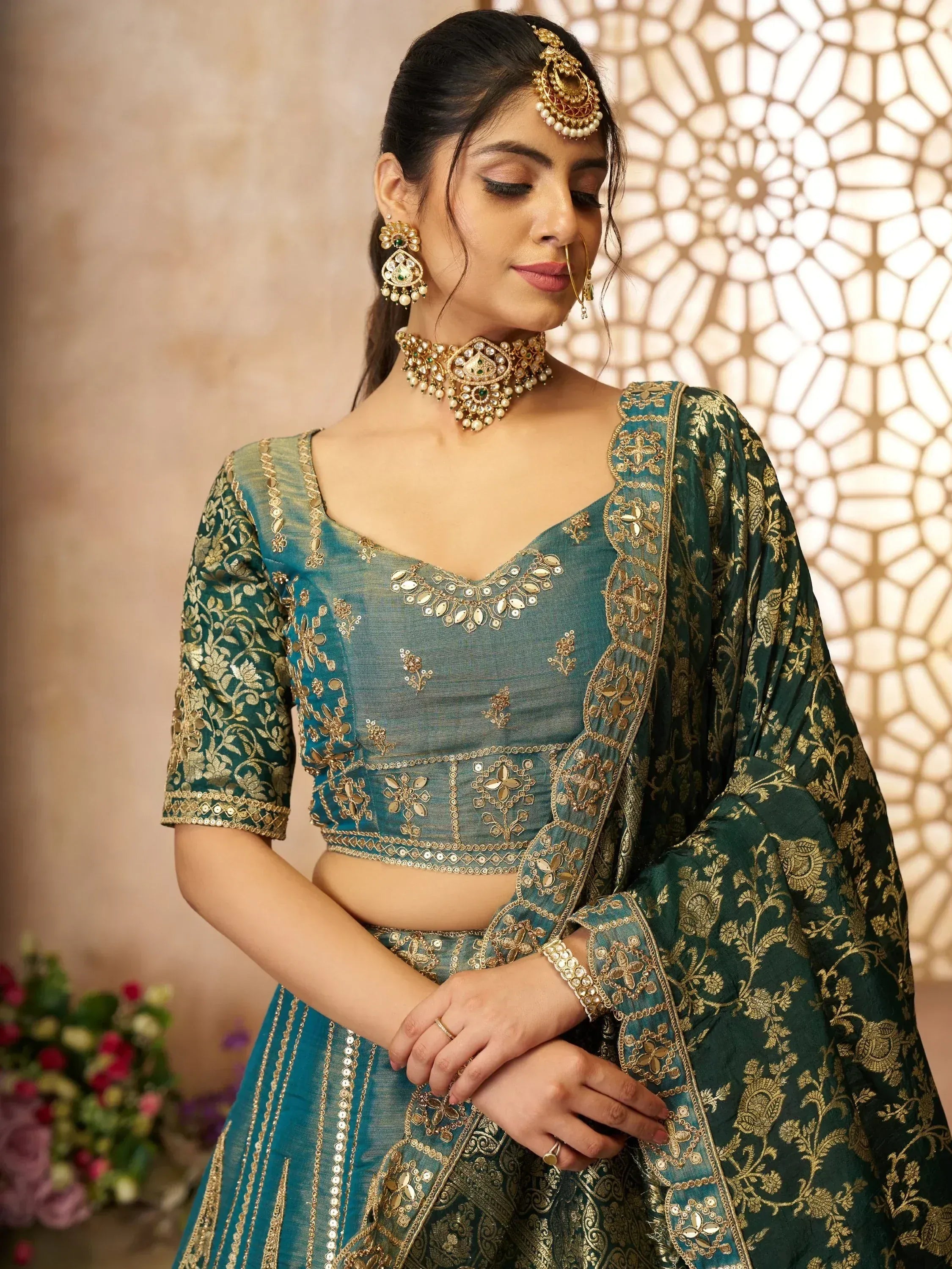 Teal and gold embroidered lehenga choli with matching dupatta and traditional jewelry for Indian ethnic wear