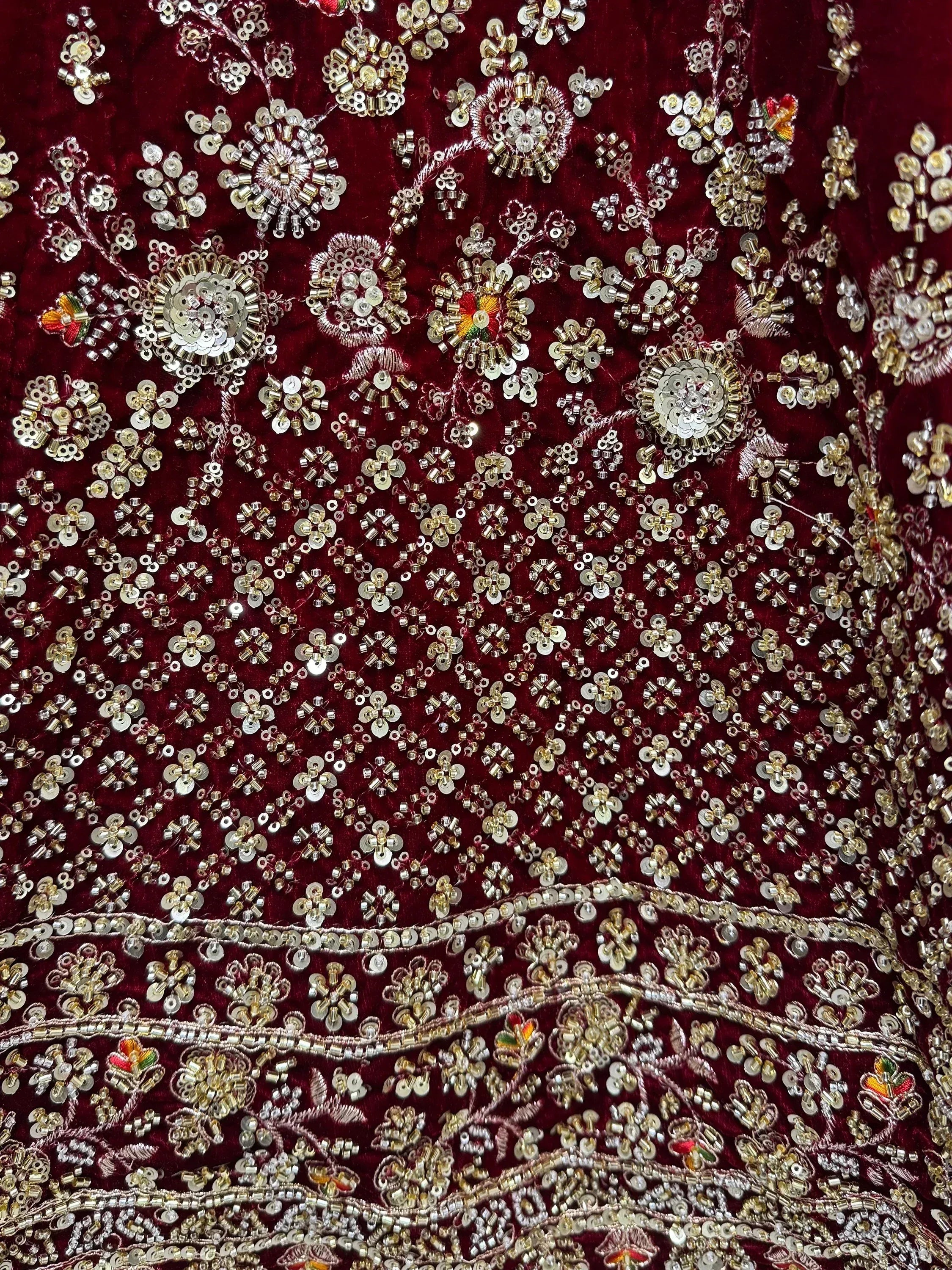 Rich maroon velvet with intricate gold and silver sequin embroidery, perfect for designer lehenga choli or ethnic gowns.