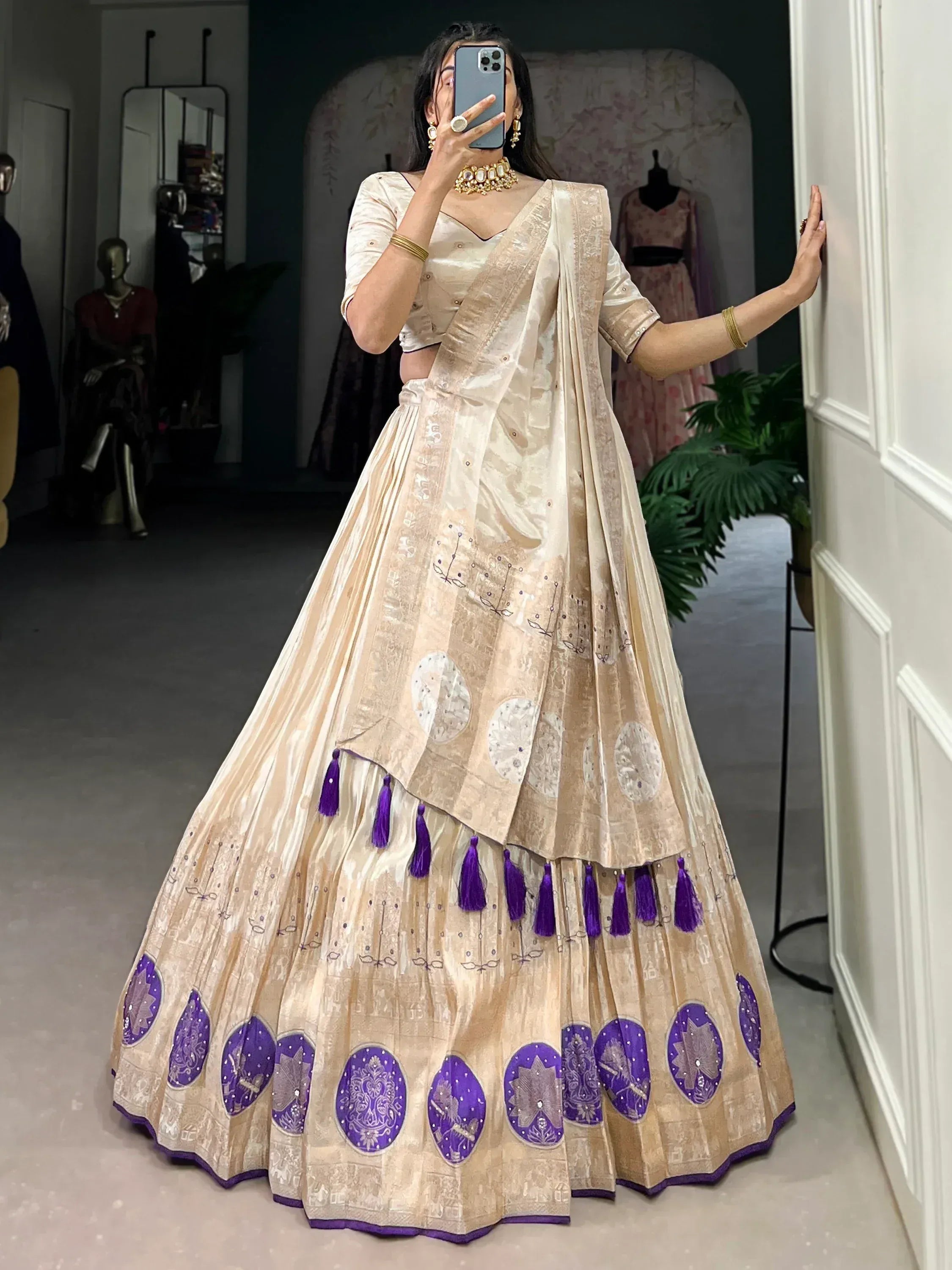 Elegant cream lehenga choli with purple embroidery and tassels, perfect for Indian ethnic wear occasions