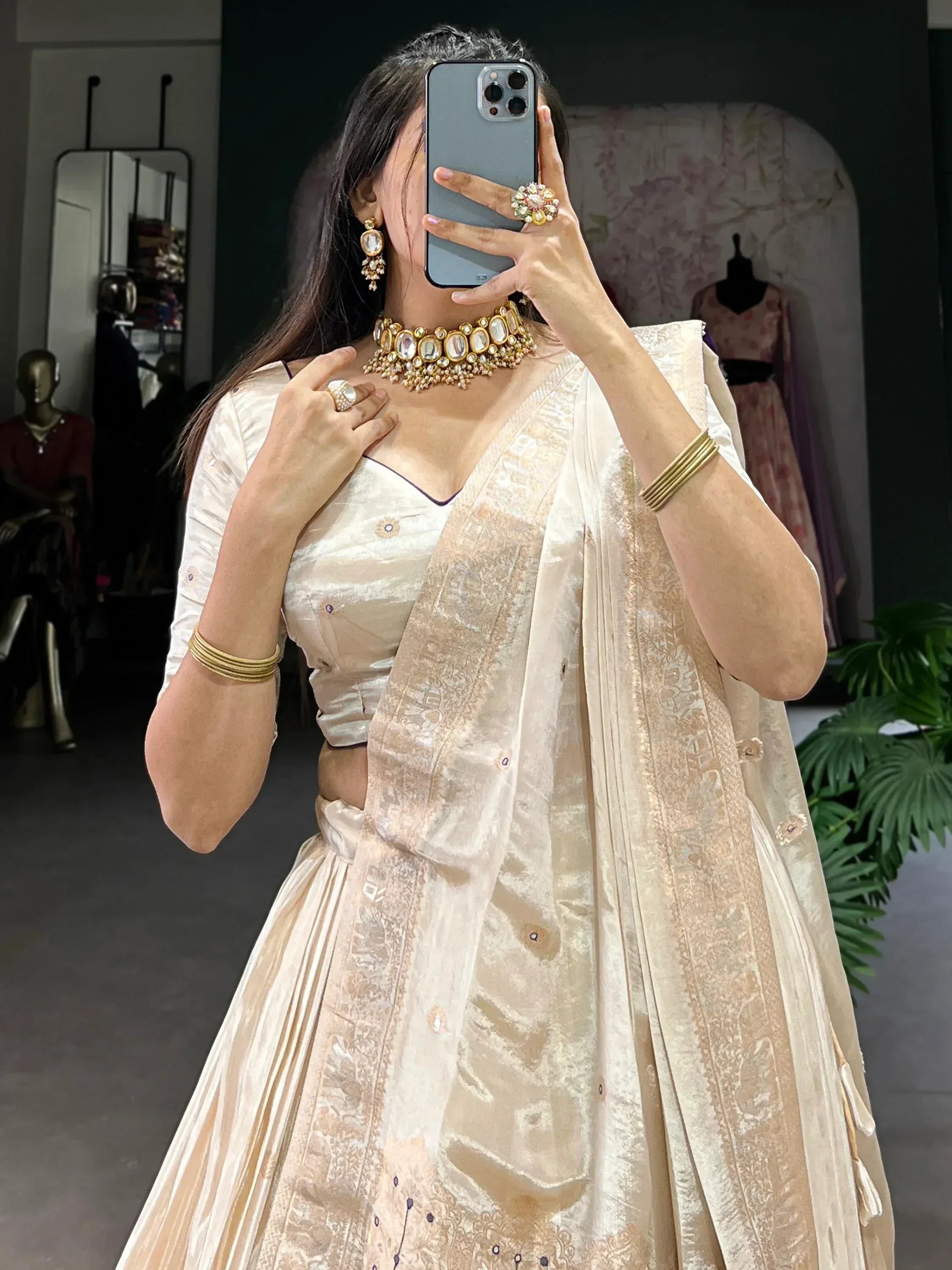 Elegant cream lehenga choli with gold embroidery, paired with traditional jewelry for Indian ethnic wear