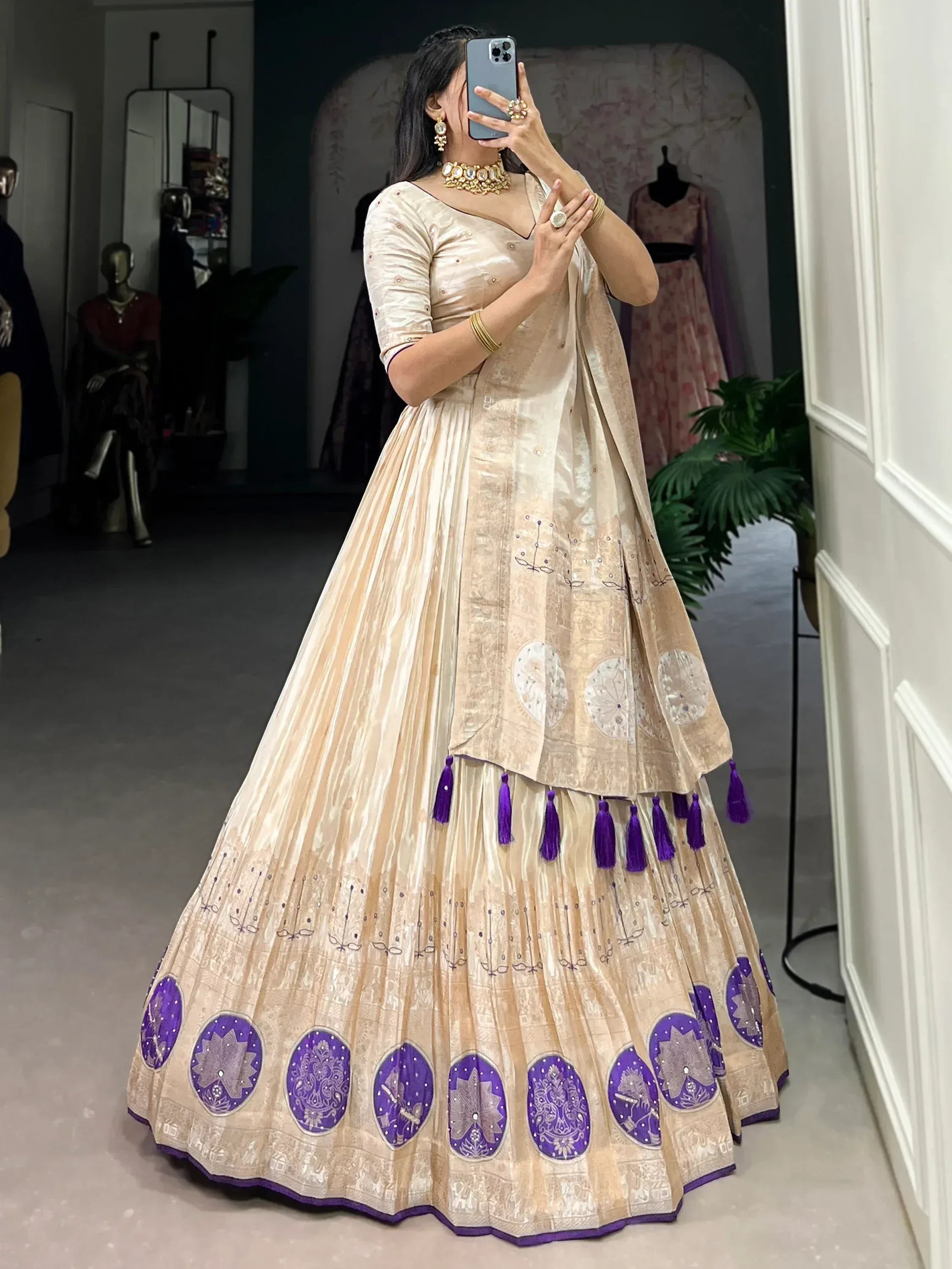 Elegant beige lehenga choli with purple floral embroidery and tassels, perfect for Indian ethnic occasions.