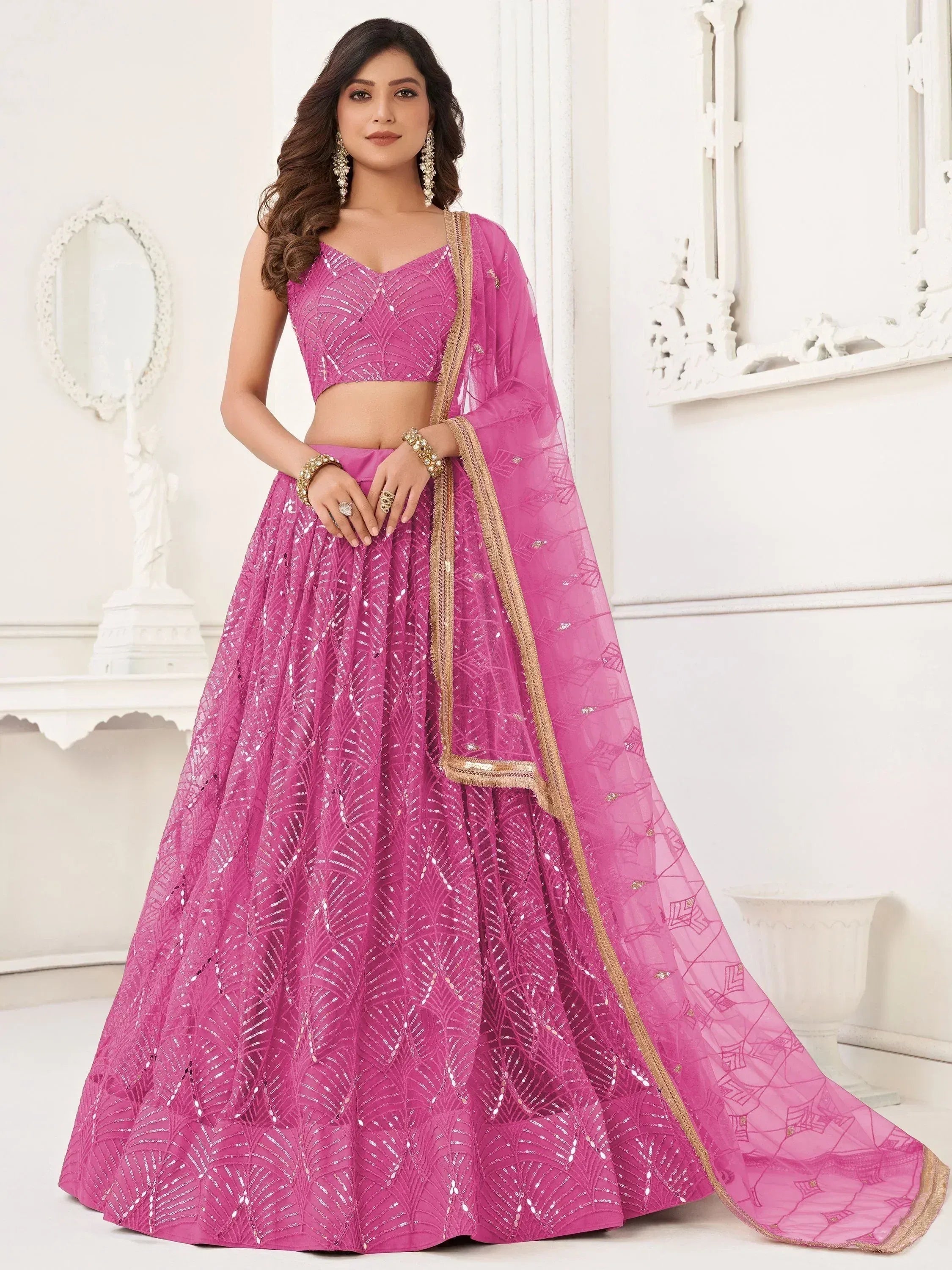 Pink designer lehenga choli with sequin work and gold trim, perfect for Indian weddings and festive occasions.