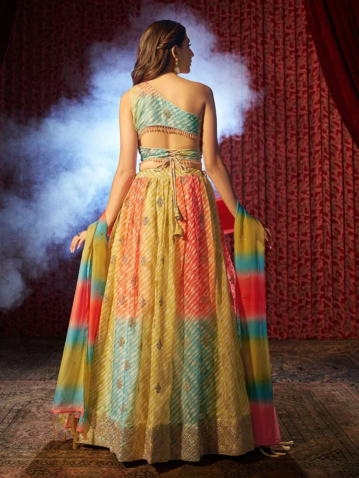 Colorful Indian lehenga choli with one-shoulder top, tie-waist, and tie-dye dupatta, perfect for festive occasions.