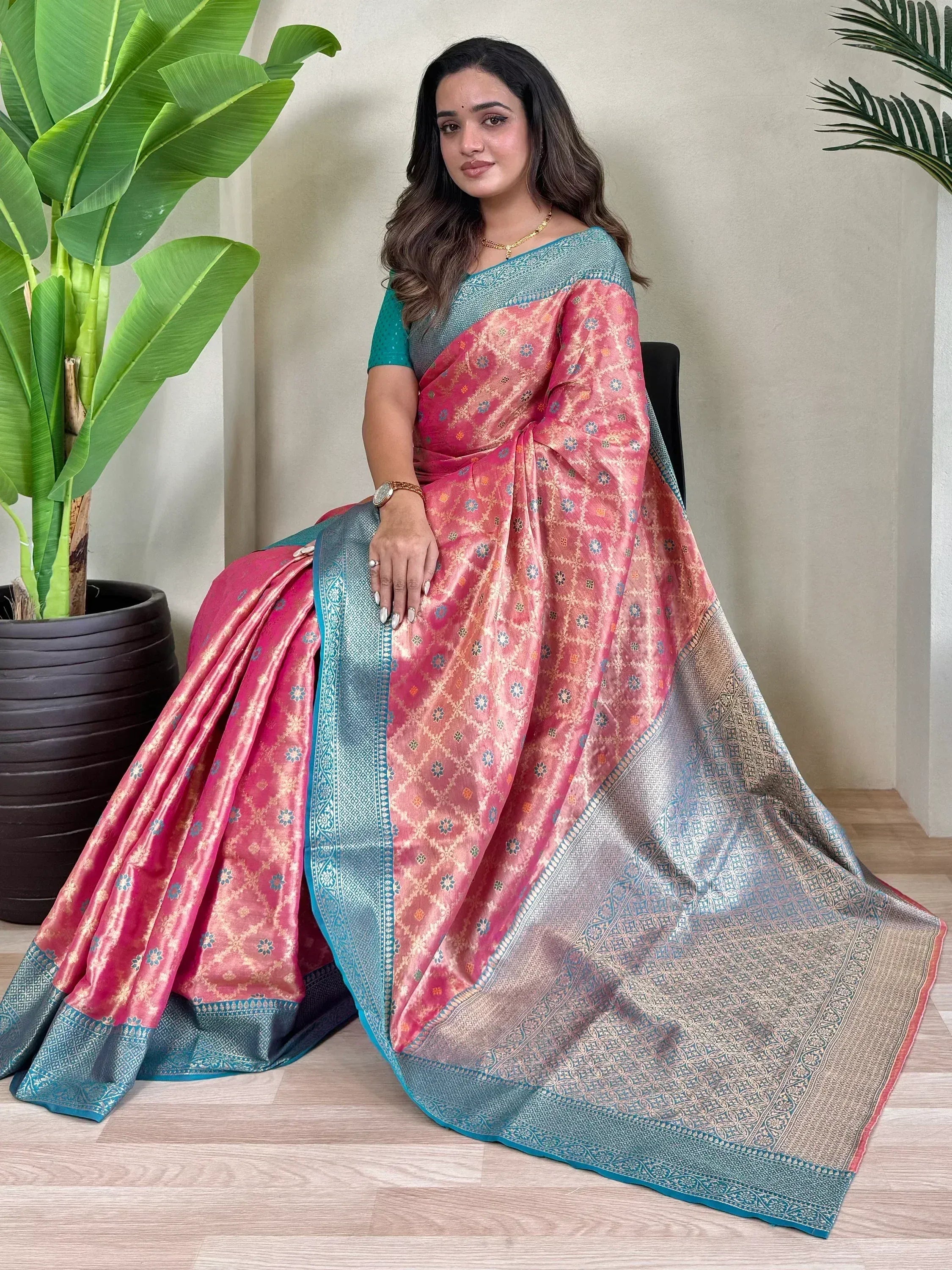 Woman in pink and teal designer saree with intricate floral patterns, perfect for ethnic occasions