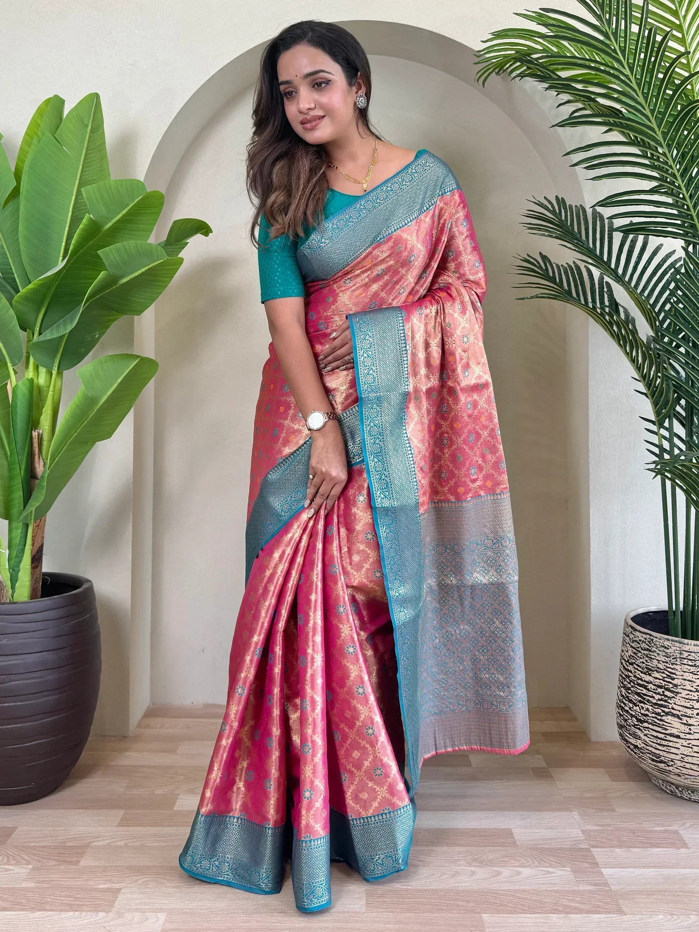 Woman in pink and teal designer saree with gold floral motifs and intricate border, perfect for ethnic occasions