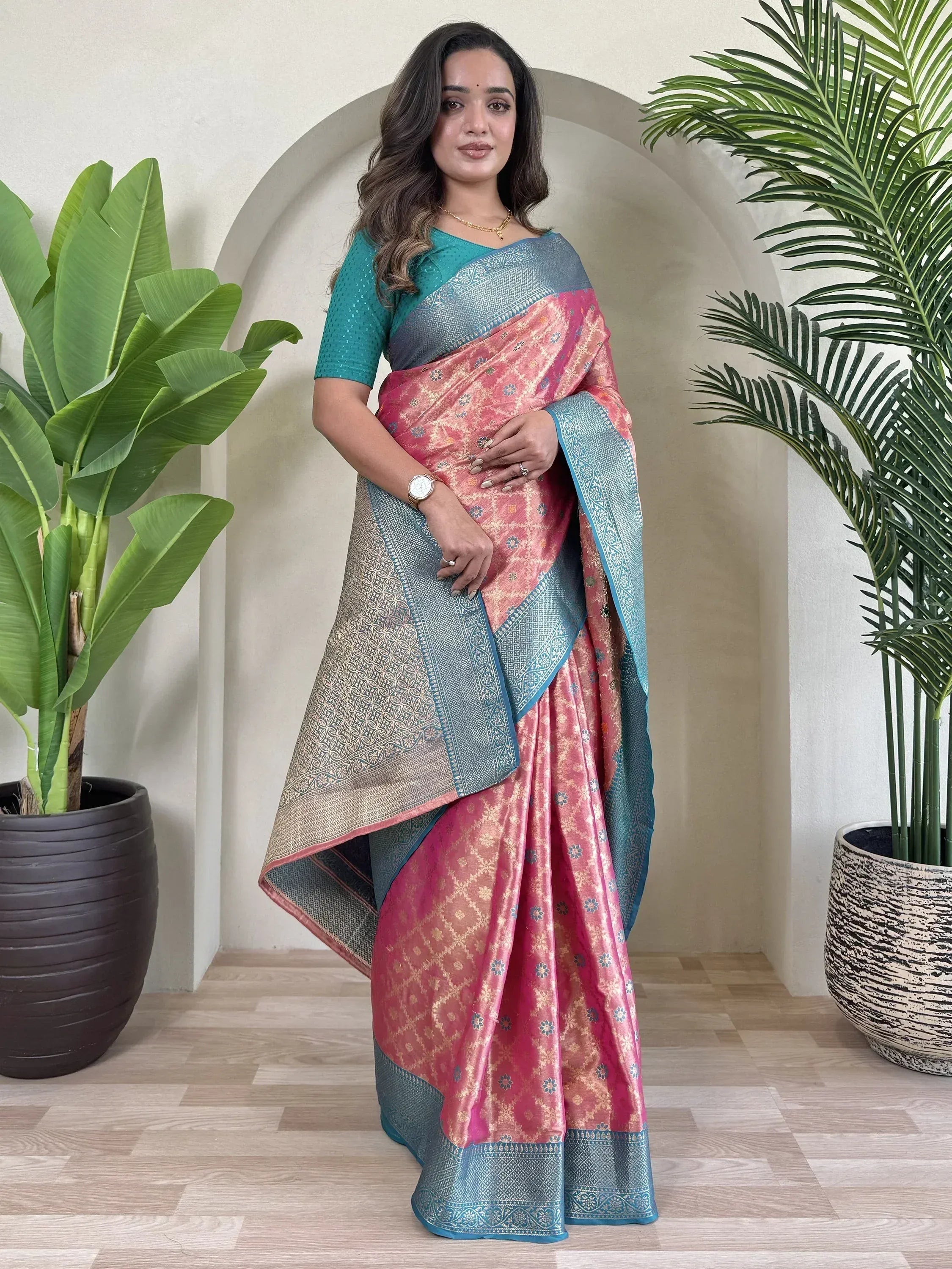 Pink and teal designer saree with gold floral motifs and intricate border, paired with matching blouse