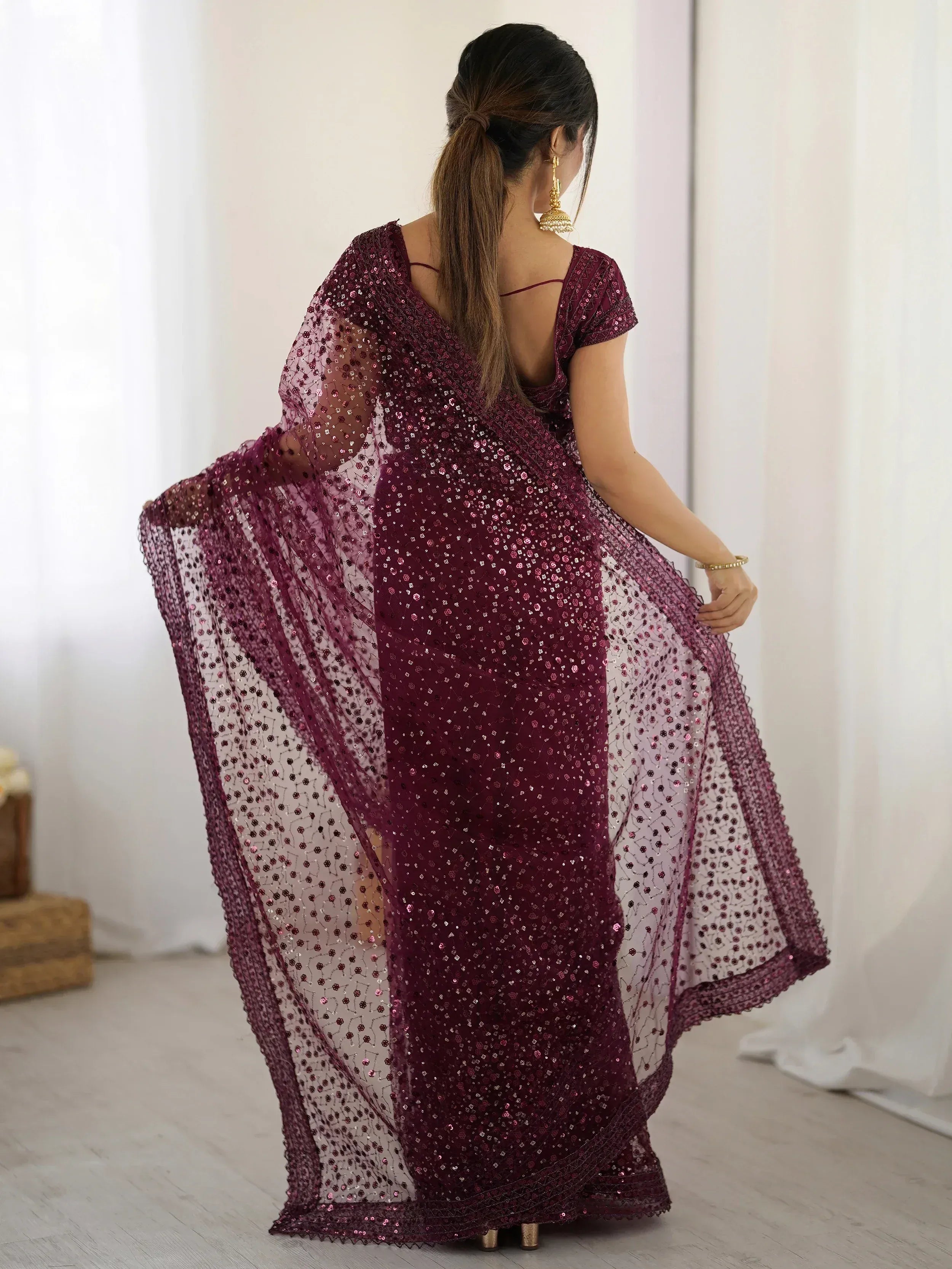 Woman in maroon sequin saree with sheer overlay, back view, ethnic wear