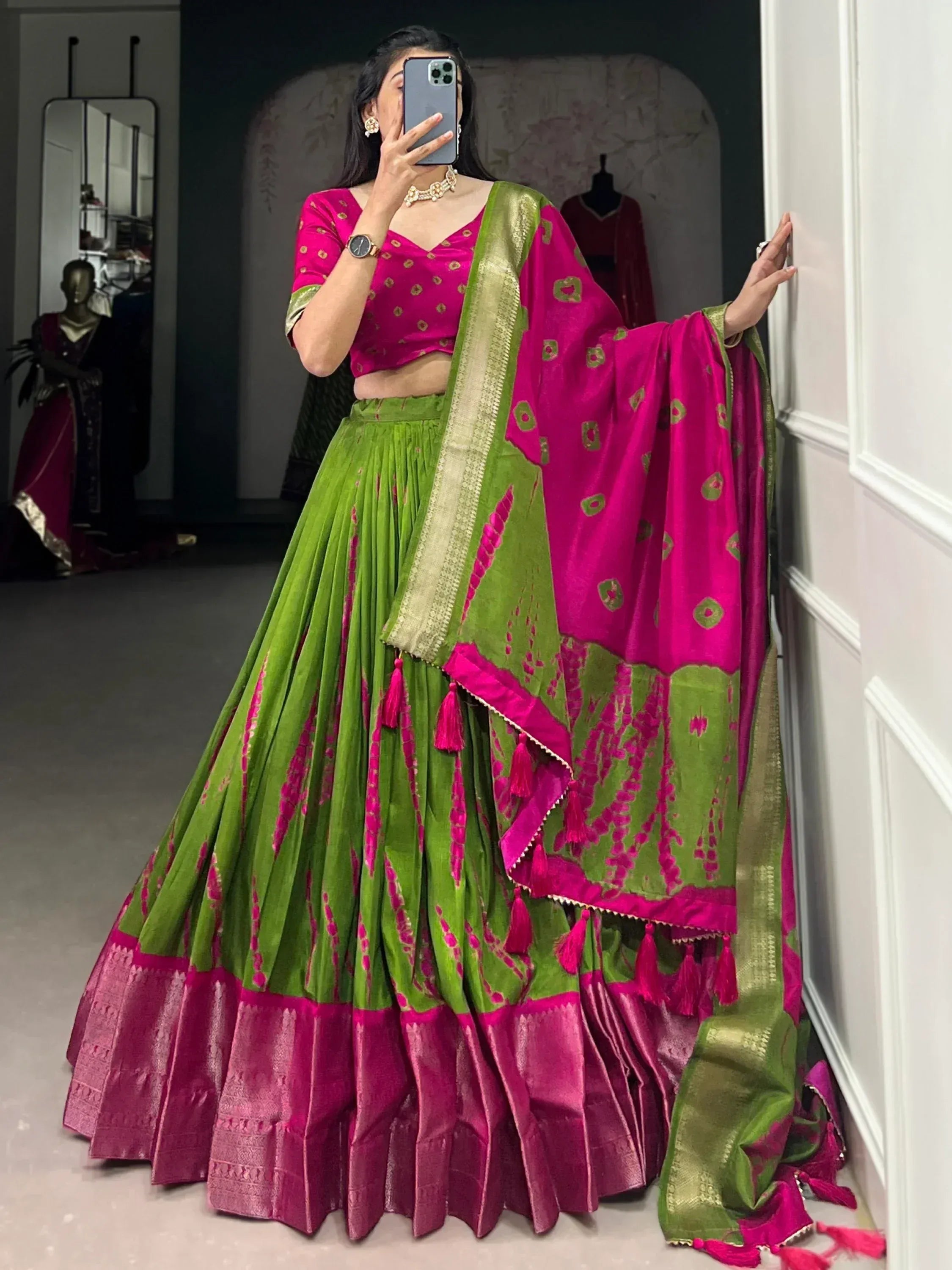 Vibrant pink and green designer lehenga choli with gold motifs and tassels, perfect for Indian ethnic wear.