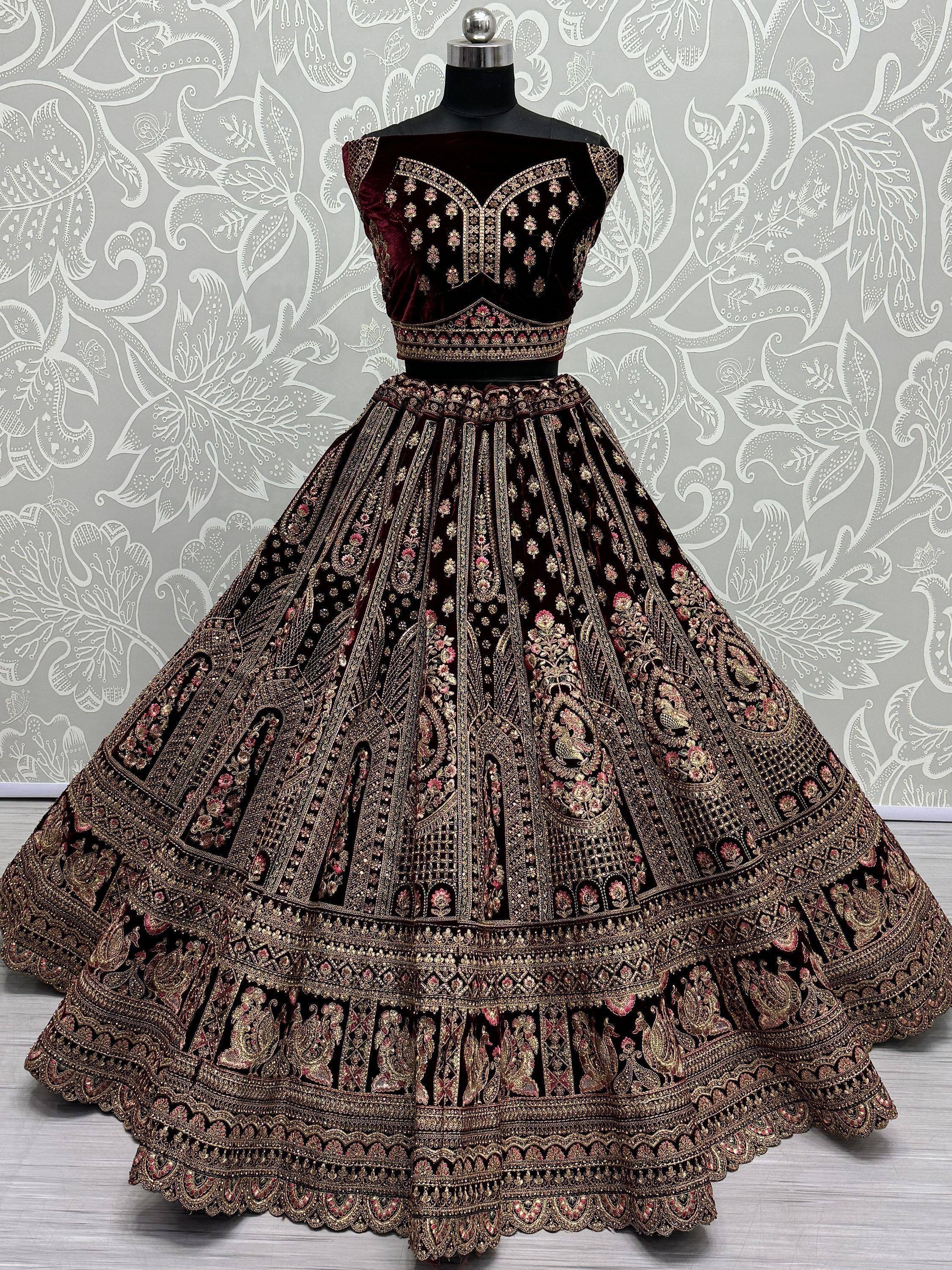 Luxury maroon velvet lehenga choli with heavy gold embroidery, perfect for Indian weddings and festive occasions.