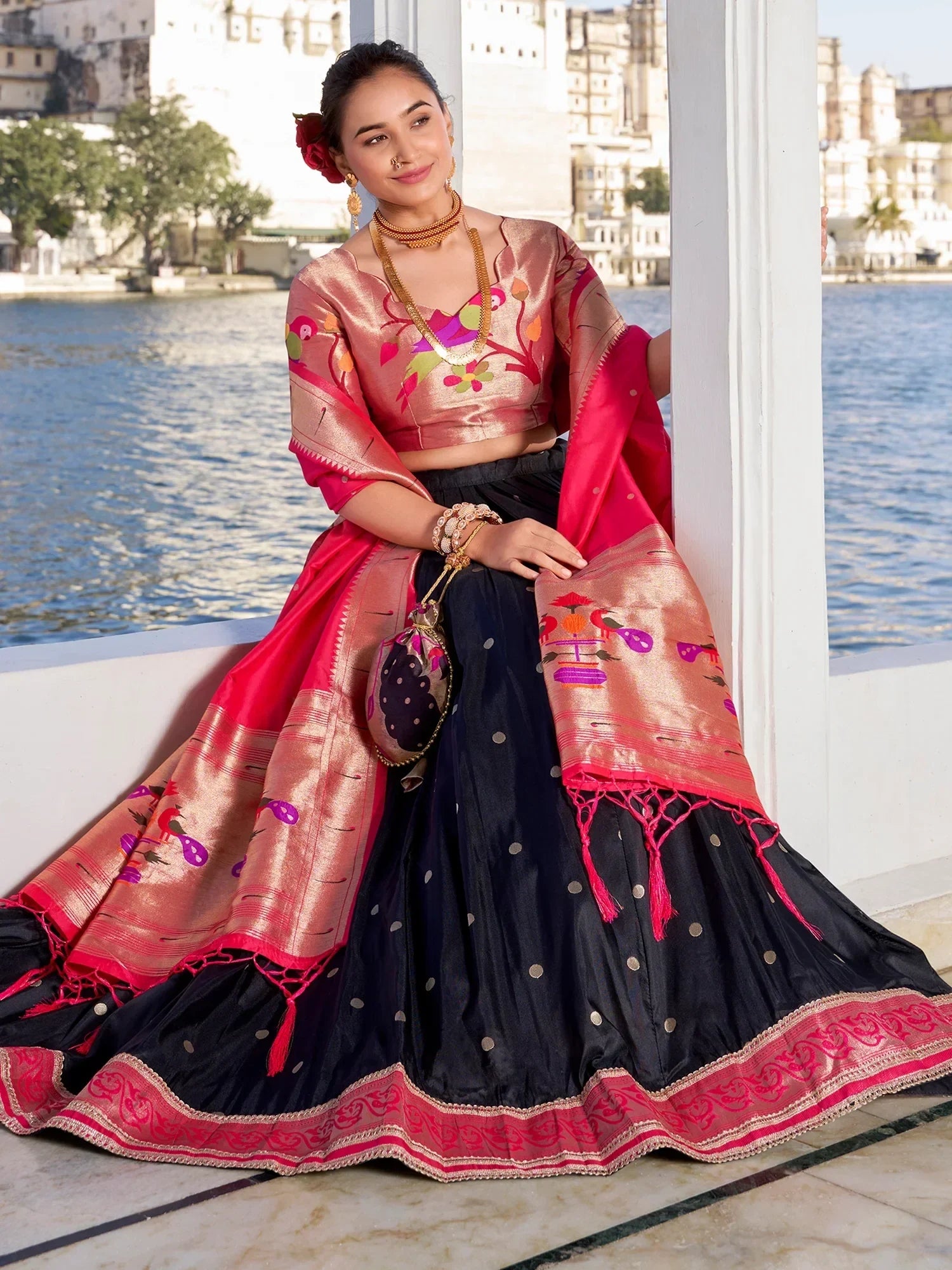 Woman in elegant Indian lehenga choli with floral embroidery, paired with dupatta, by lakeside palace backdrop