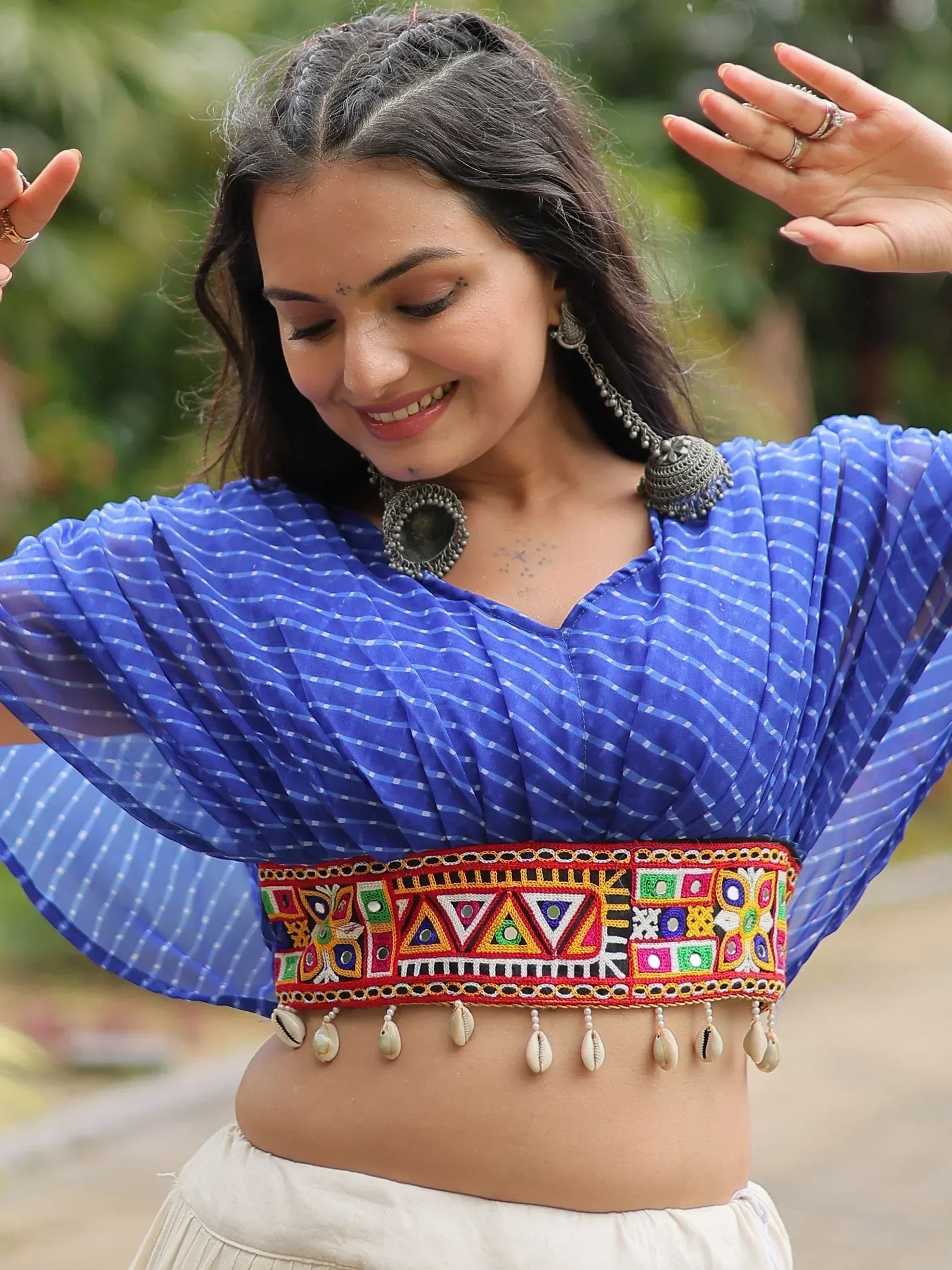 Blue ethnic crop top with mirror work and shell tassels, paired with traditional jewelry for festive Indian wear