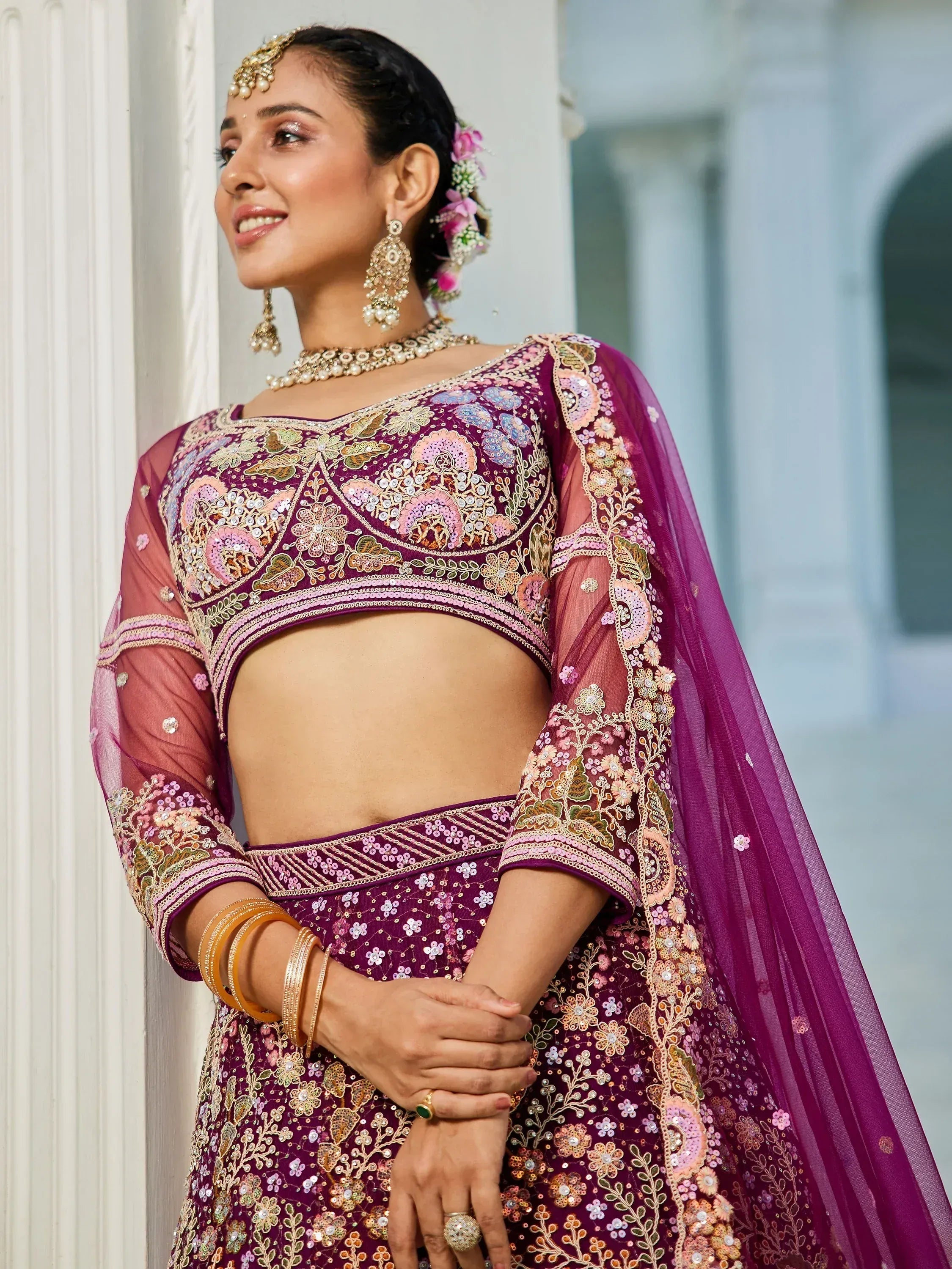 Elegant purple embroidered lehenga choli with floral motifs and sheer sleeves, perfect for Indian weddings and festive occasions.