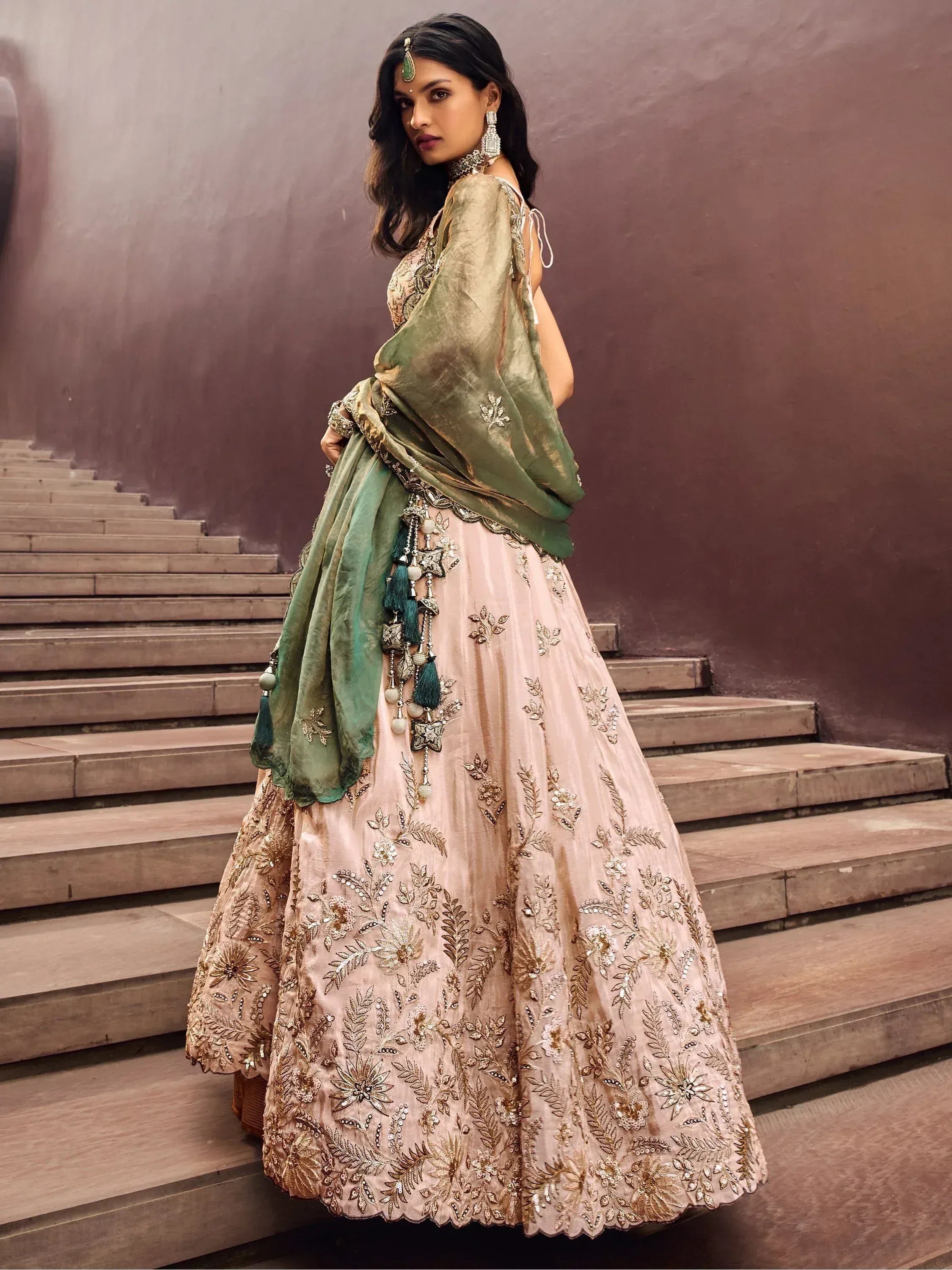 Elegant blush lehenga choli with gold embroidery and green dupatta, perfect for Indian weddings and festive occasions.
