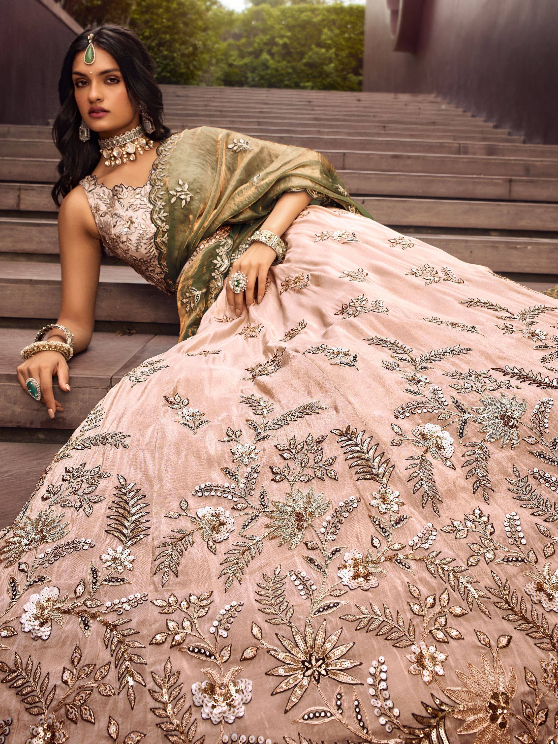 Elegant blush pink lehenga choli with gold floral embroidery and green dupatta, perfect for Indian weddings.