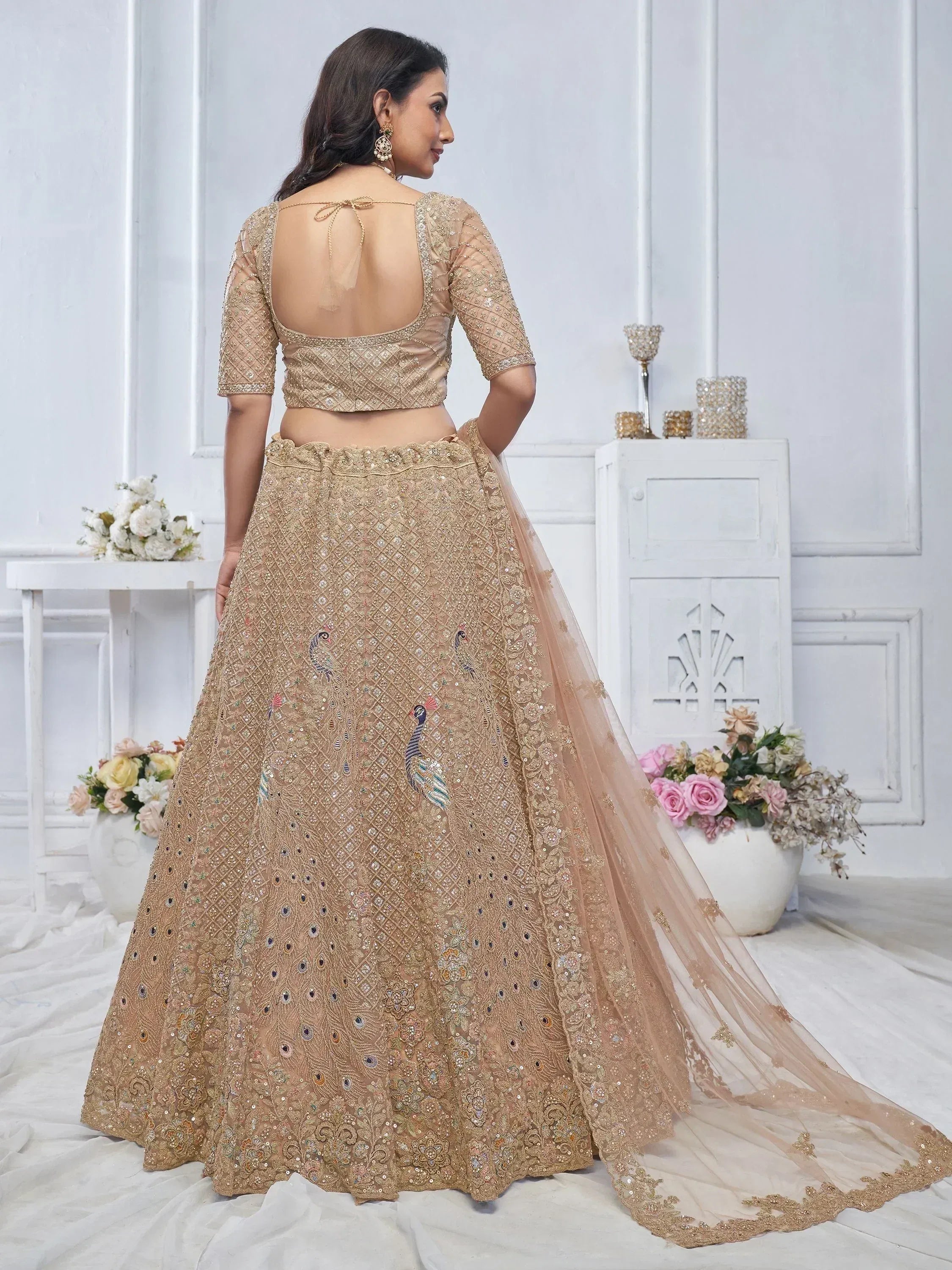 Beige designer lehenga choli with peacock embroidery, backless blouse, and sheer dupatta for weddings