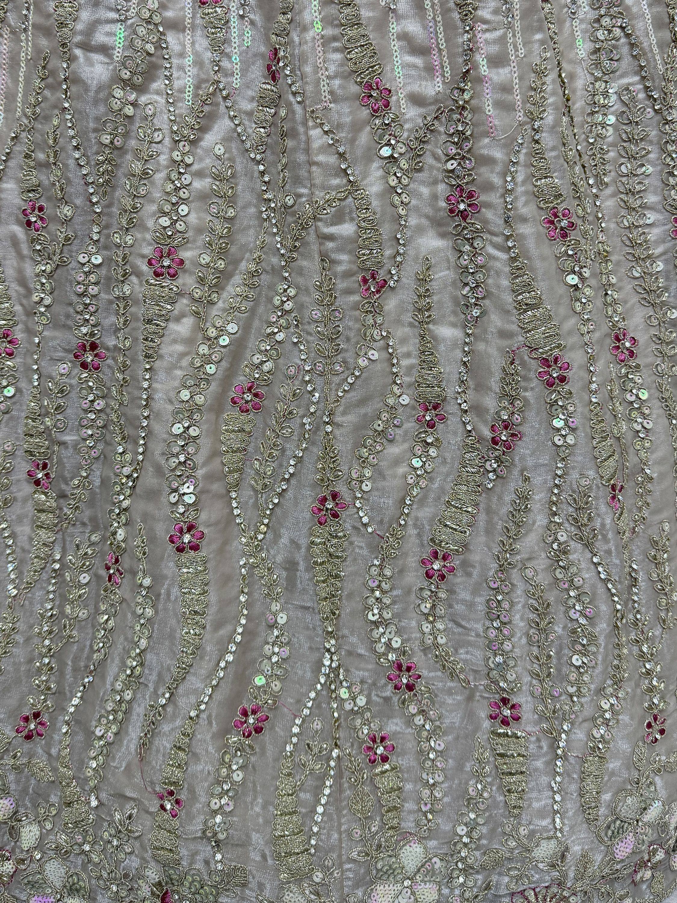 Elegant Indian ethnic wear with intricate gold embroidery, pink floral motifs, and shimmering sequins on soft fabric.