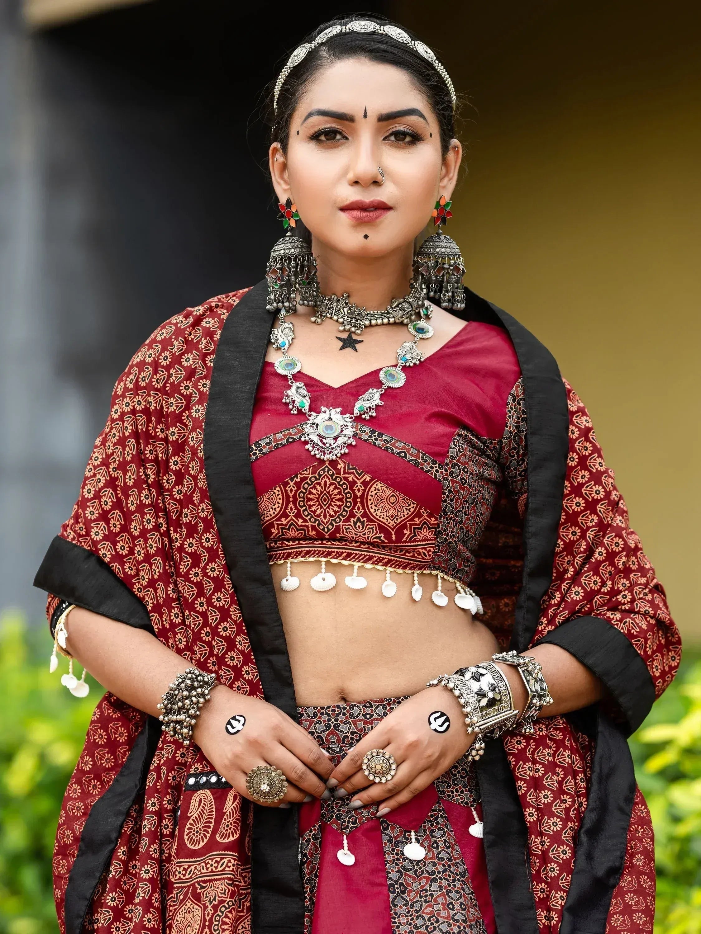 Woman in maroon ethnic lehenga choli with silver jewelry and floral dupatta, traditional Indian attire