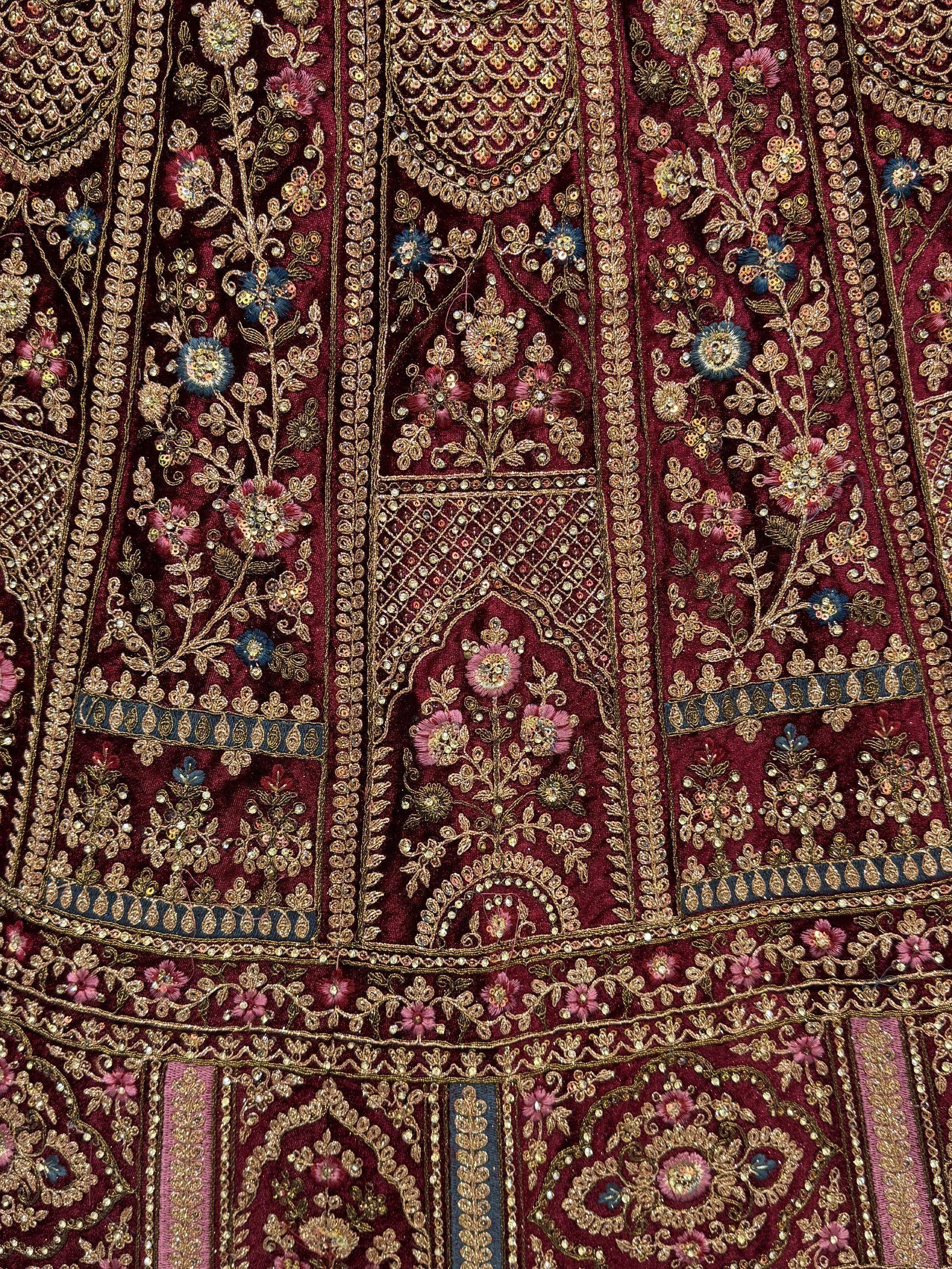 Rich maroon Indian ethnic wear with intricate gold embroidery, floral motifs, and sequin detailing for festive occasions.
