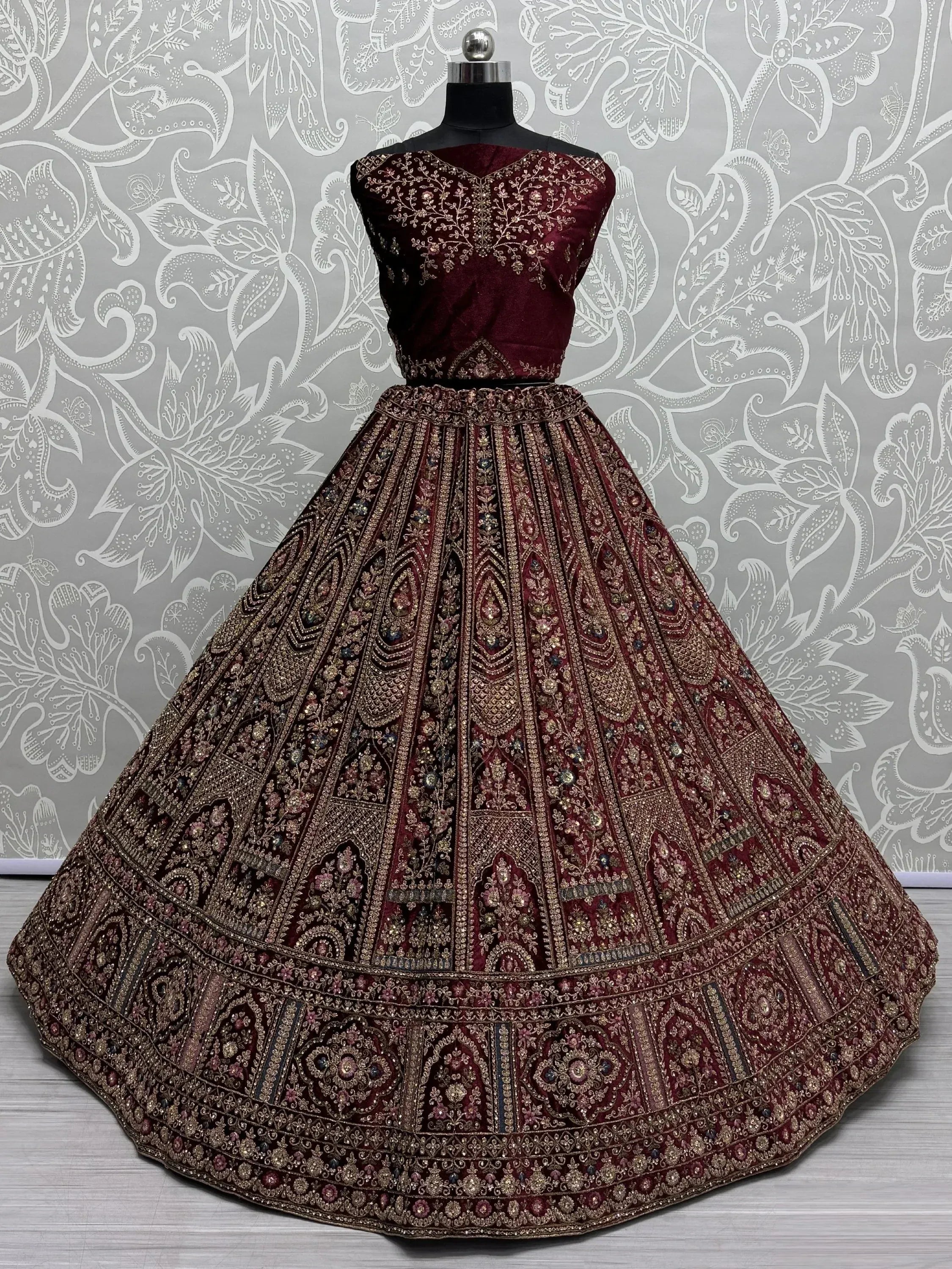Maroon velvet designer lehenga choli with heavy gold embroidery and floral patterns, perfect for weddings