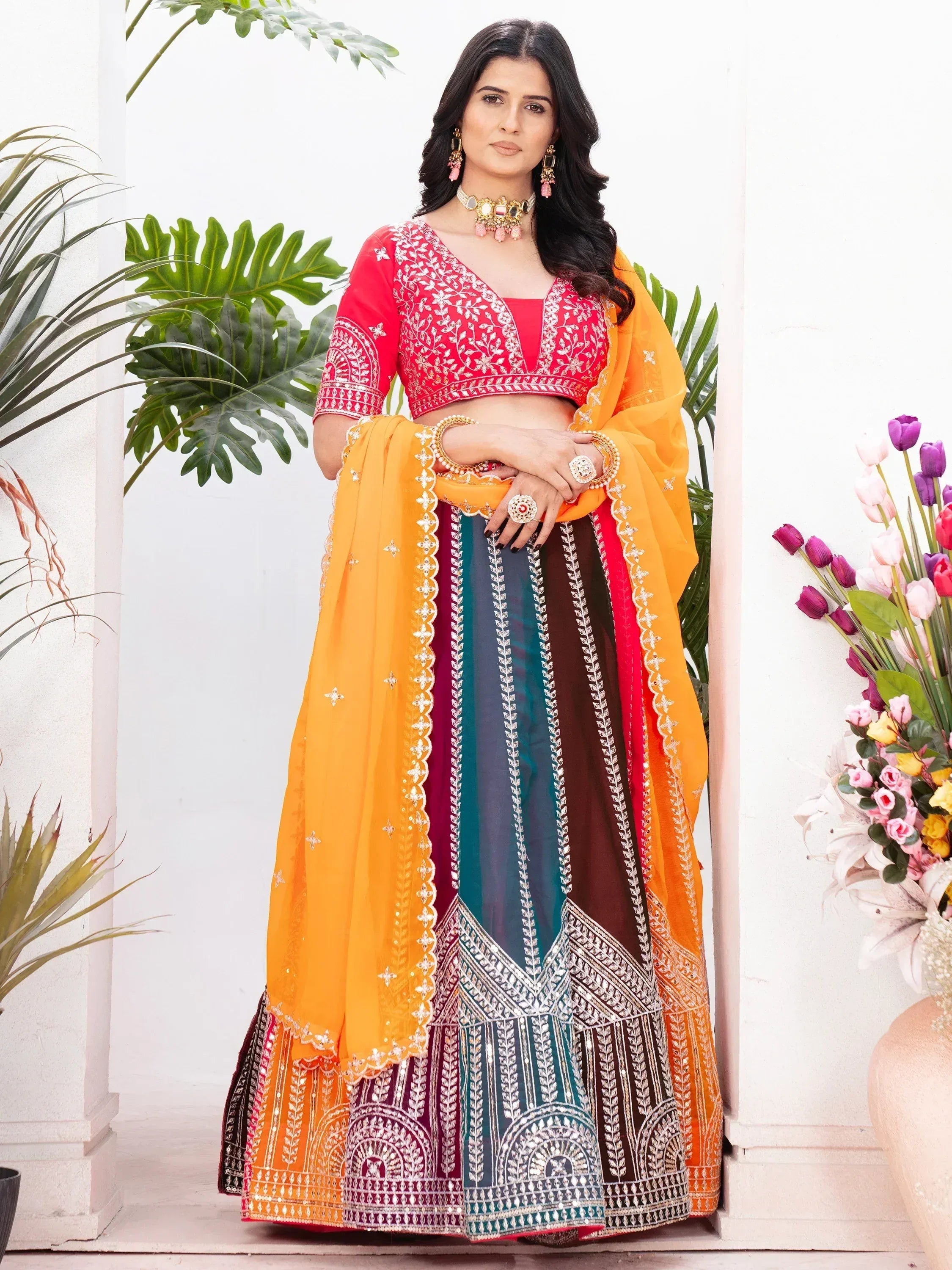 Vibrant Indian lehenga choli with red blouse, multicolor skirt, and orange dupatta, perfect for festive occasions.